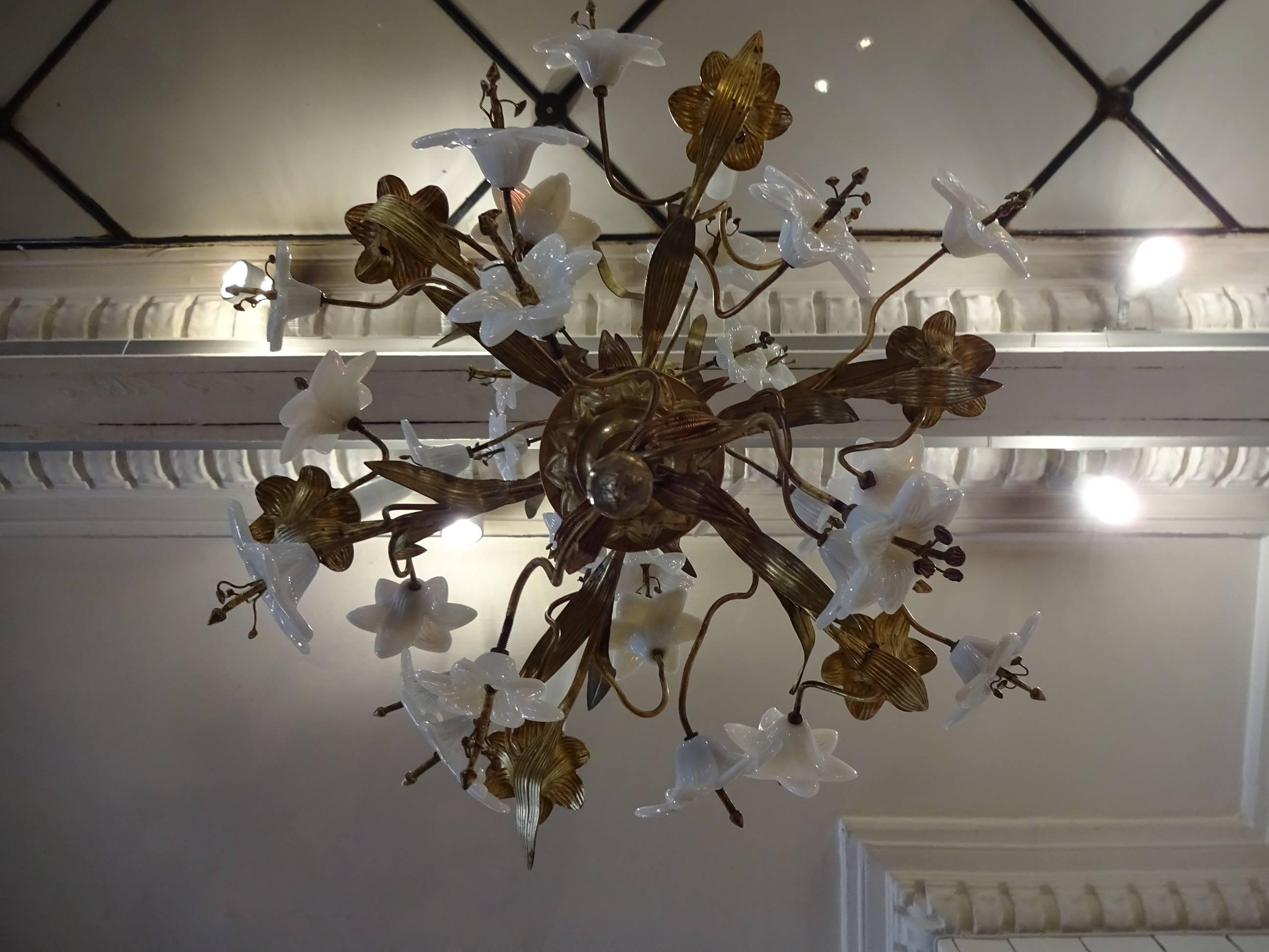 Antique French church chandelier in gilt bronze and brass with countless beautiful lilies in white opal glass and space for six candles. The chandelier has many details as small acorns at the lower end and a beautiful rosette in the supporting chain.