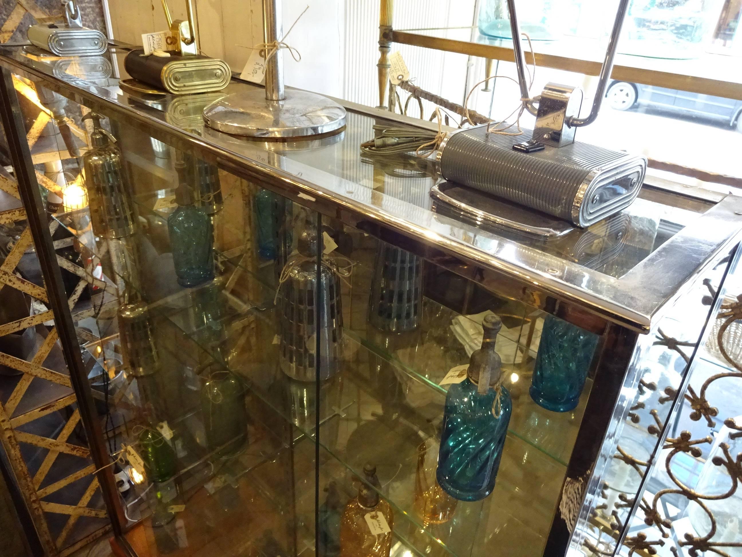 Big and very beautiful old French chrome display cabinet with three rectangular glass shelves, mirrored back wall and wooden base.