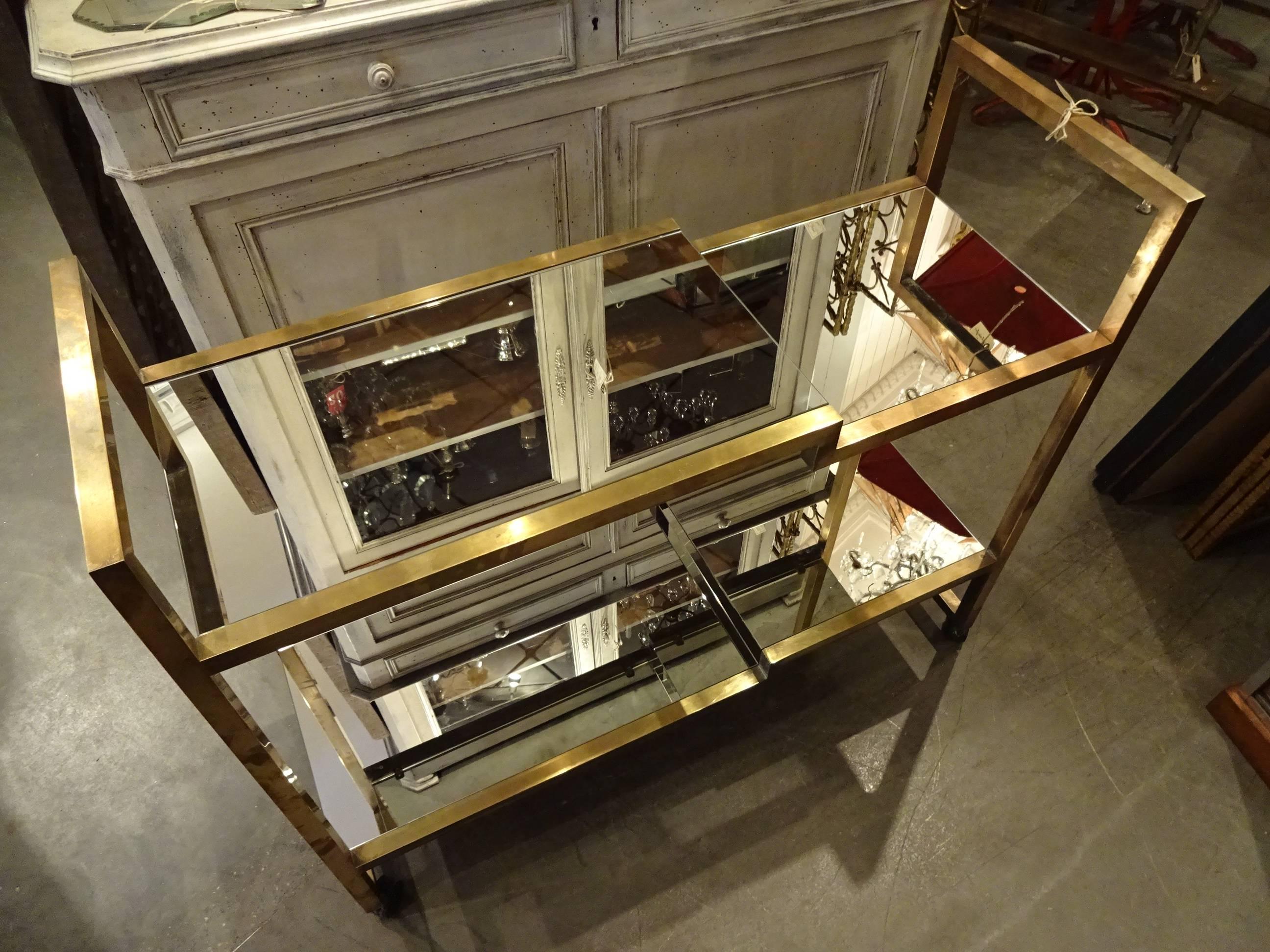 Fantastic vintage French Mid-Century, 1950s brass shelving unit on wheels with mirrored glass shelves. Absolutely gorgeous piece. Lots of practical uses, but also would make a great room divider.