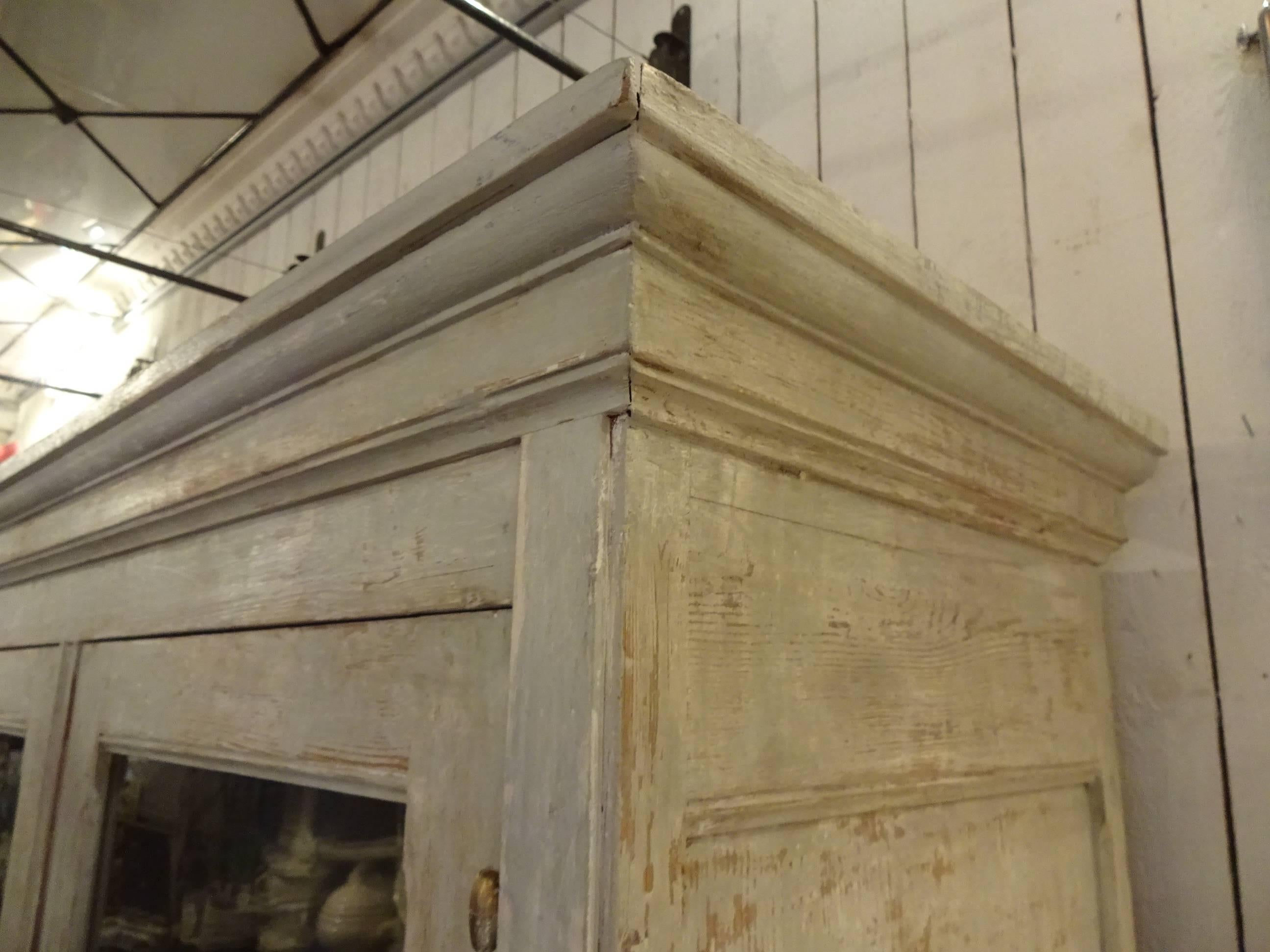 Gorgeous old French grey patinated display cabinet with brass grips and hinges. The upper part of the cabinet har four doors with the original blown glass. Behind these two shelves. Inner part painted in a beautiful matte blue grey colour. The lower