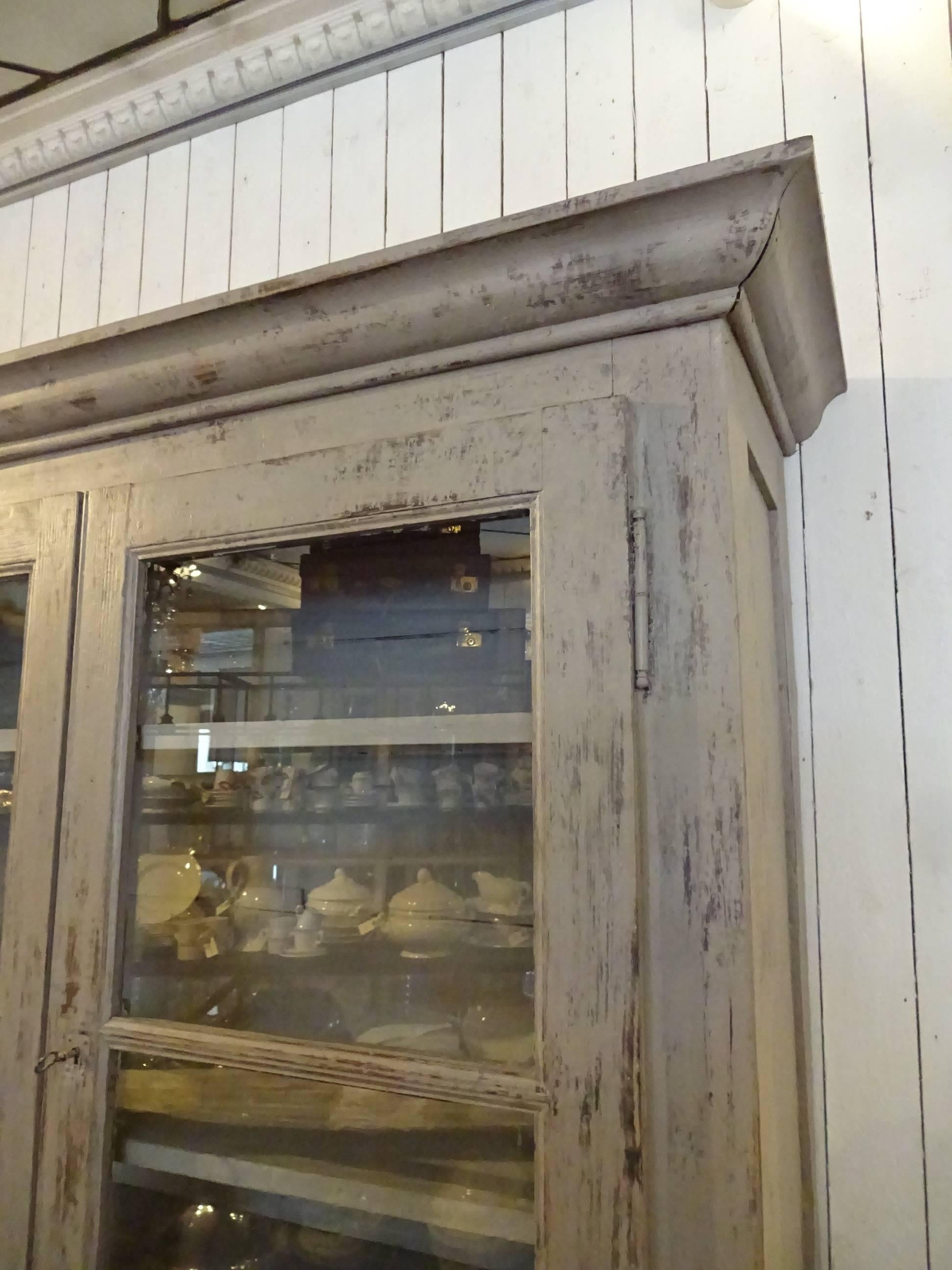Beautiful vintage French grey or painted cabinet with nice detailing. The cabinet has two glass doors, behind these three shelves and an additional shelf in the cupboard underneath. Stunning patina.