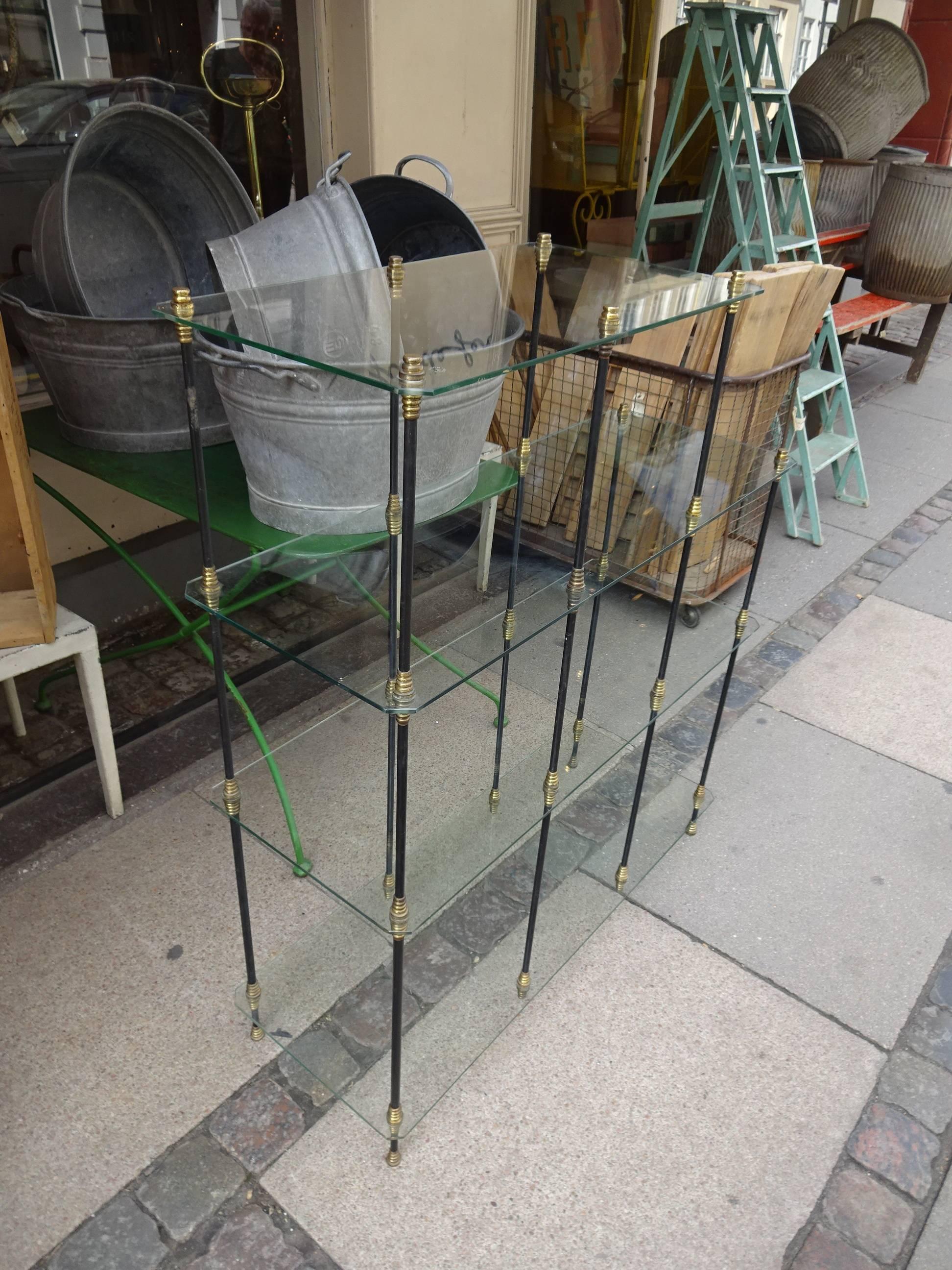 Elegant vintage French shelving unit. Beautifully made with slim elegant black rod legs and with decorative brass fittings and thin glass plates shelves. A beautiful and practical unit.