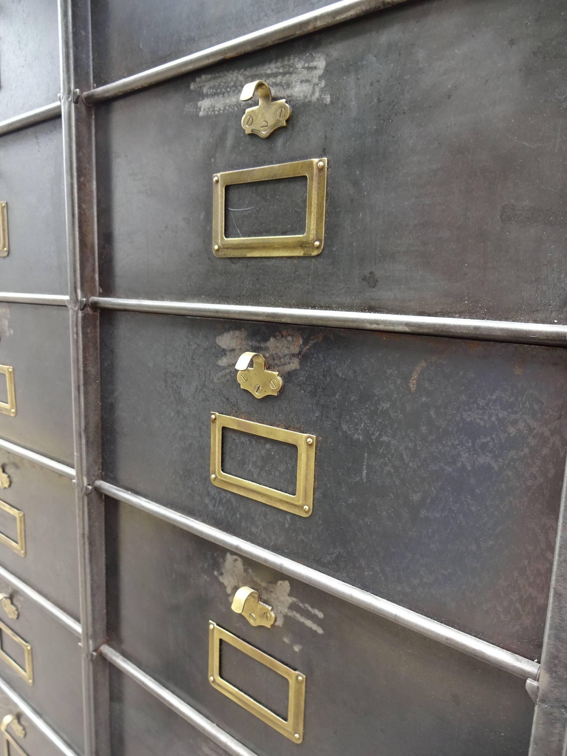 Raw large file cabinet in desolate and polished metal color. The cupboard appears both elegant and raw at the same time, with the fine brass grip and label holders, and has 30 compartments.