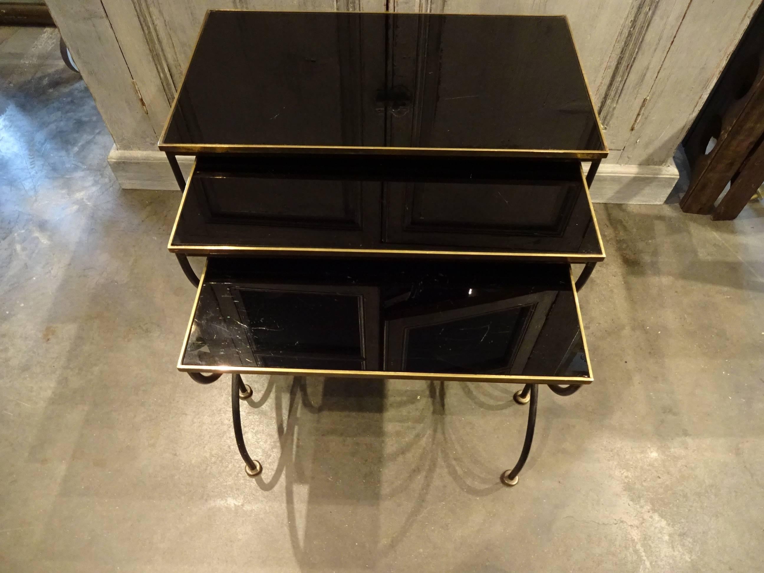 A set of three elegant French nesting tables. Brass frame, with black opaque glass surfaces. Lovely leg detailing. Would look fabulous whether coffee tables, bedside tables or side tables.