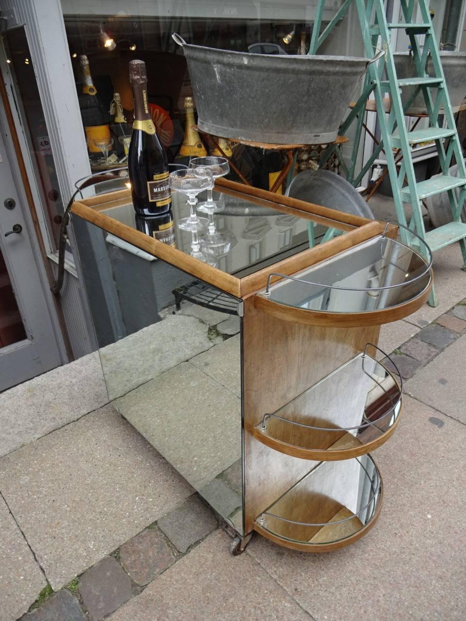 This wonderful French drinks cart/bar trolley displays all the hallmark elements of the Classic “ocean liner” Art Deco design of the 1930s. The rounded ends, with the polished chrome railings, simulate a ships deck. The etched mirror front door
