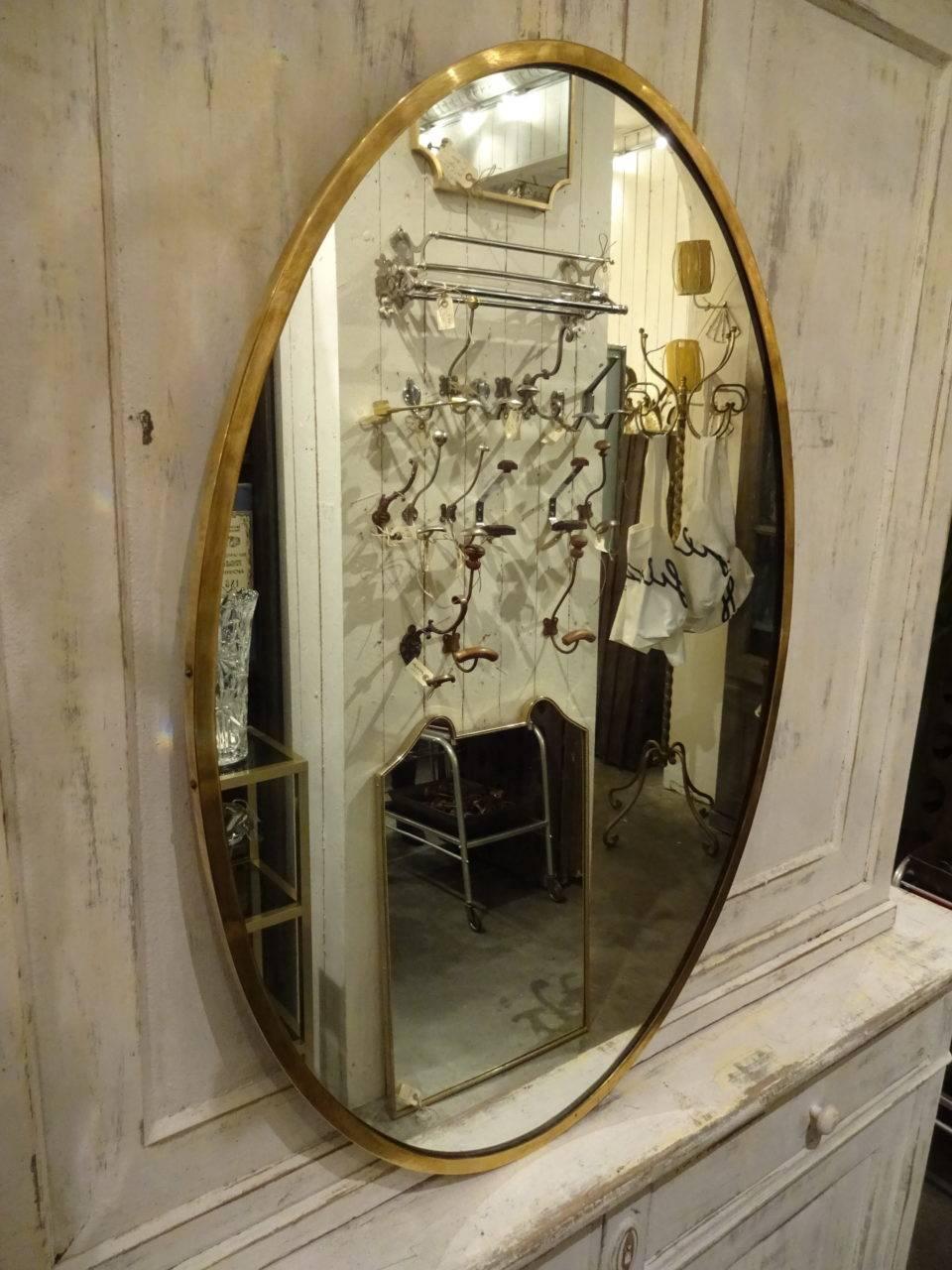 Elegant oval Italian brass mirror from the 1950s and with a style akin to Gio Ponti mirrors. Perfect for anywhere in the home.
