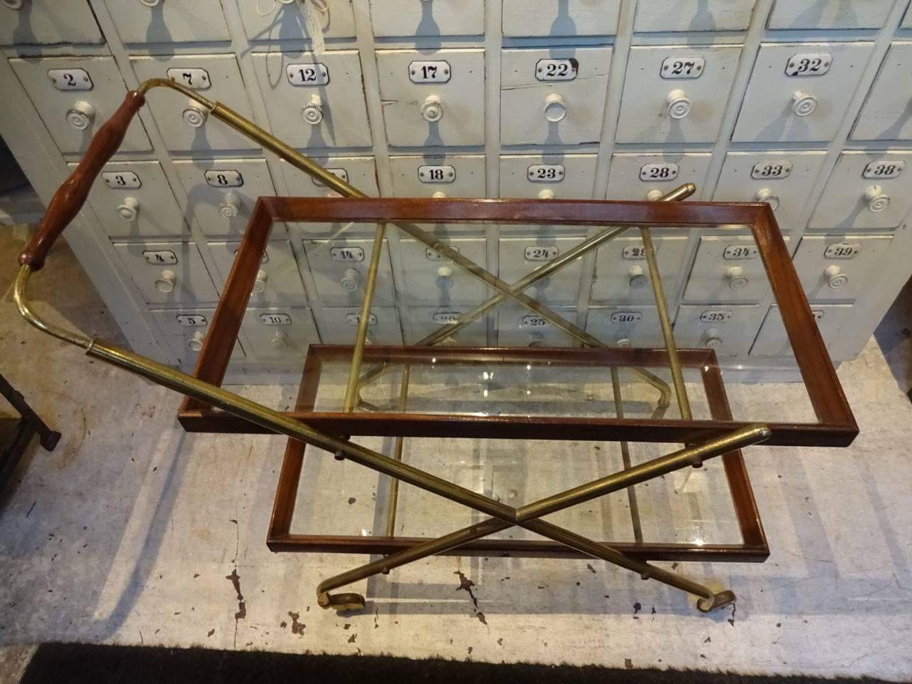 Fabulous and stylish retro bar trolley / serving cart, comprised of brass, with two rectangular glass shelves and a wooden frame. Elegant coasters / wheels and super for any kitchen or living space.