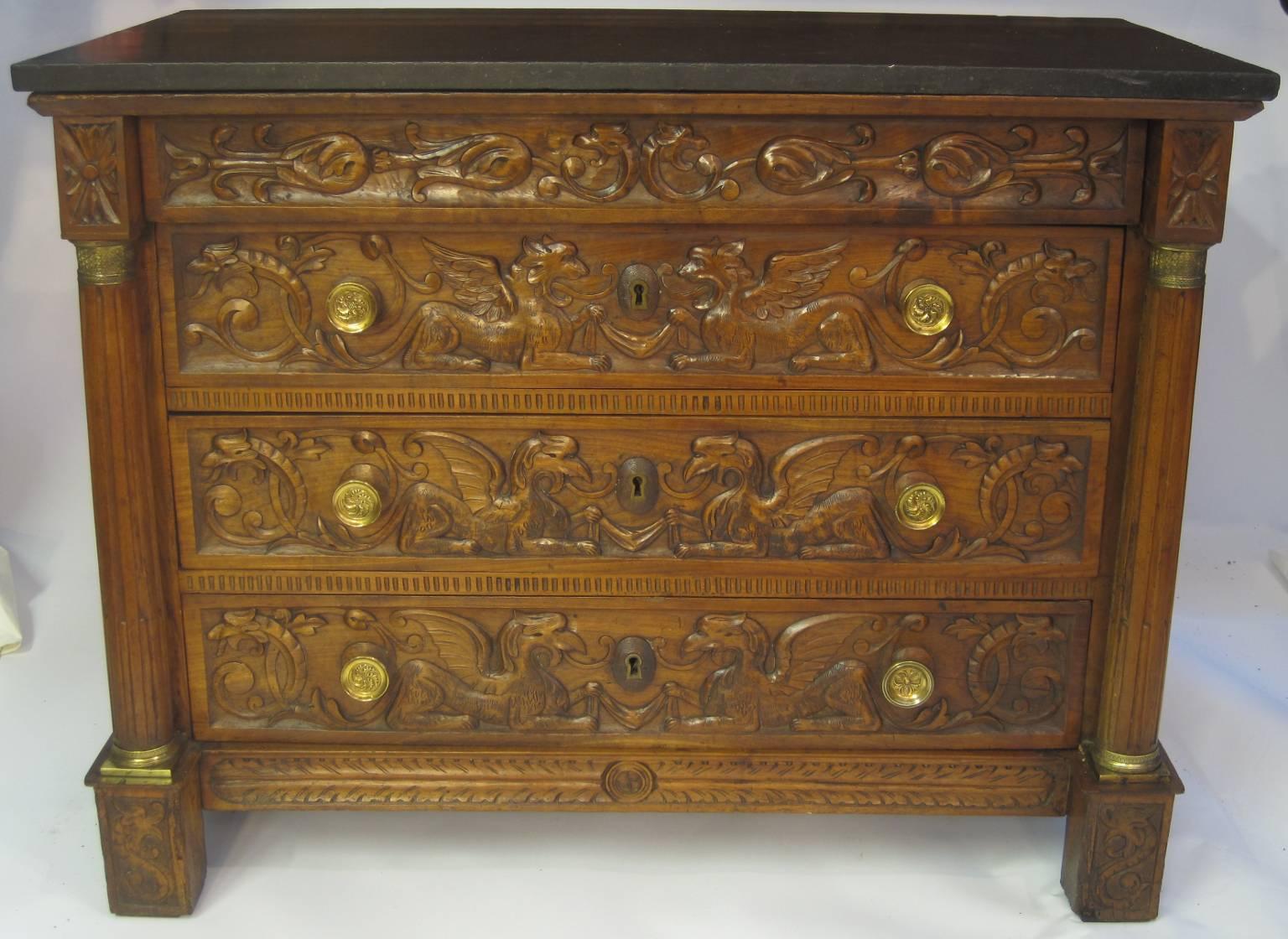 An Empire chest circa 1815 comprising three long drawers and one concealed drawer. All drawers are intricately carved with griffins, foliage and other mythological figures. Flanking the drawers are fluted tapered columns terminating in decorative