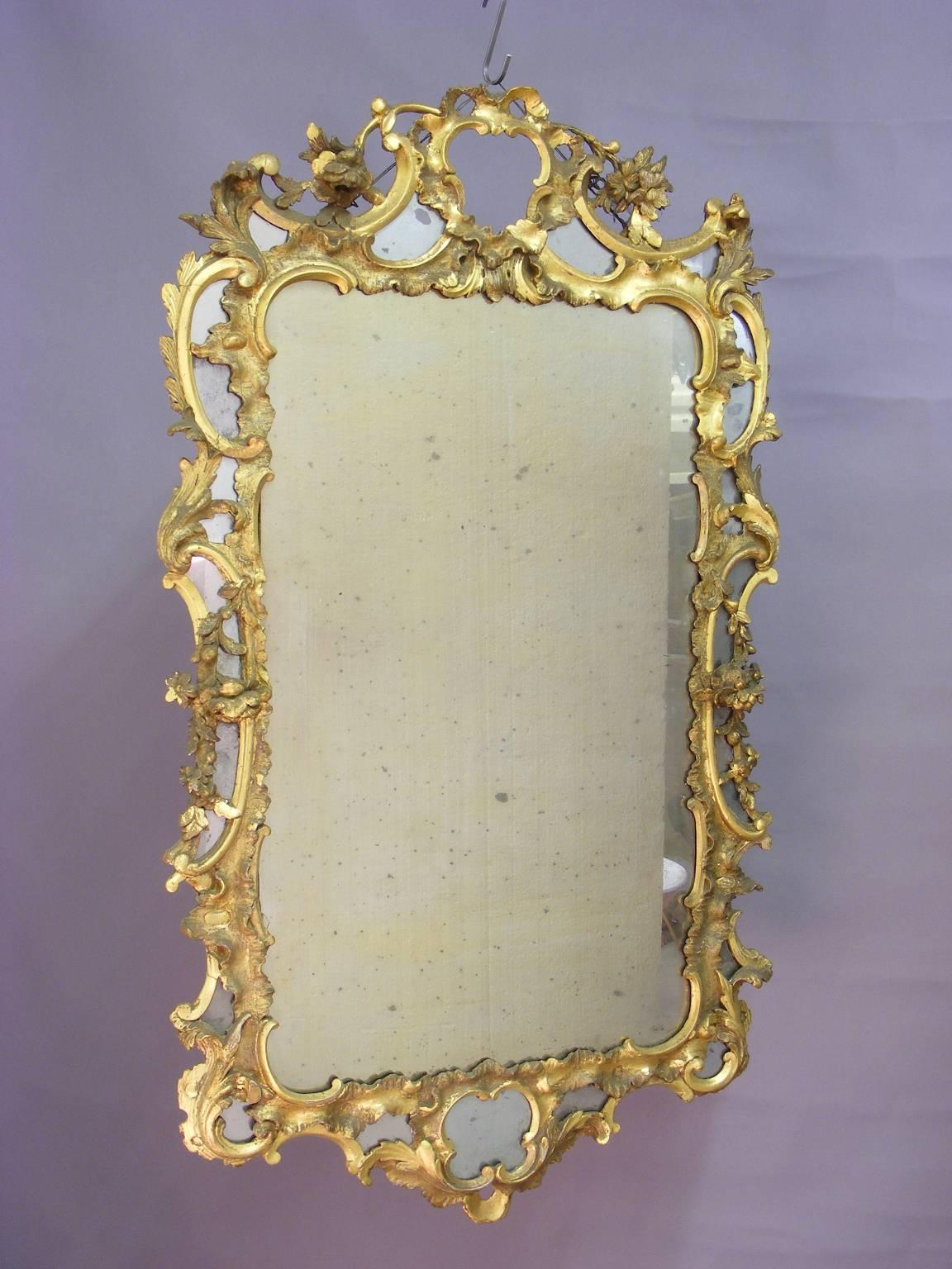 A fine George II original period (circa 1750) wood carved and gilt mirror retaining the original glass. Enclosed within a beautifully carved and gilded frame, this large magnificent piece is adorned with ‘C’ scrolls, foliated and floral decoration.