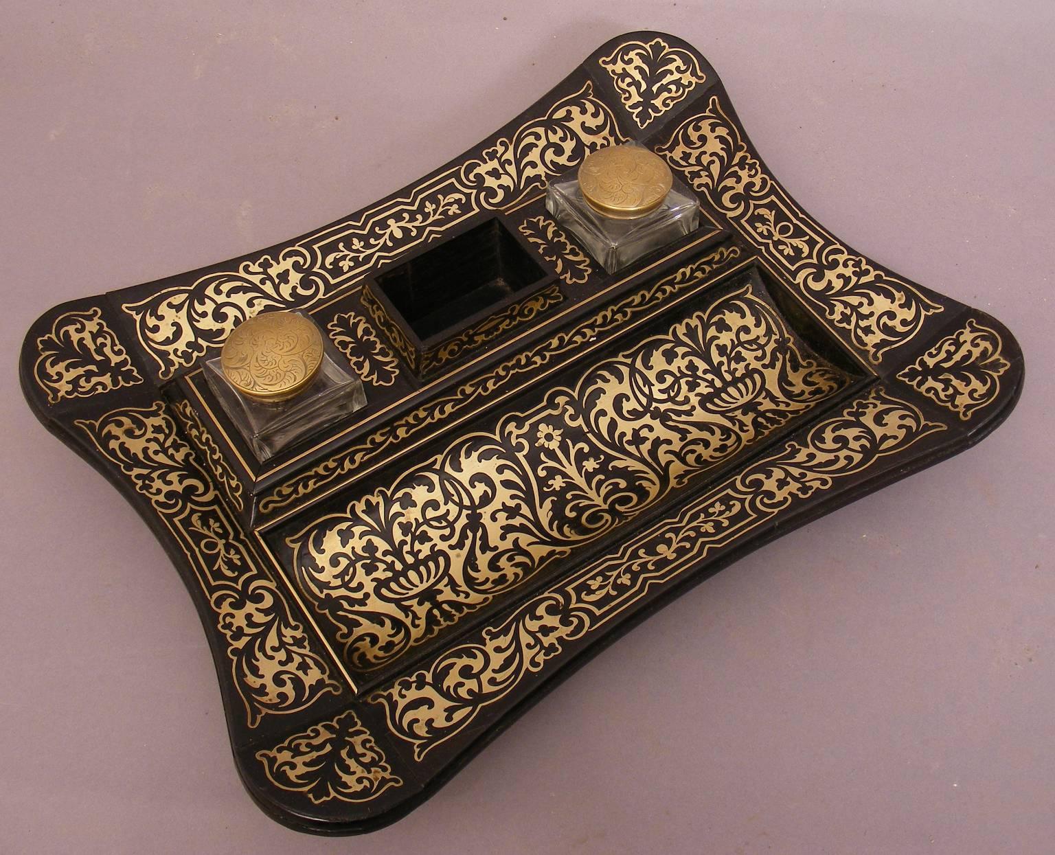A superb pen and ink stand of the Regency period. Inlaid with brass on an ebony and rosewood frame. It retains the original glass ink wells with screw on brass lids engraved with a floral motif.

This piece is in excellent condition and would