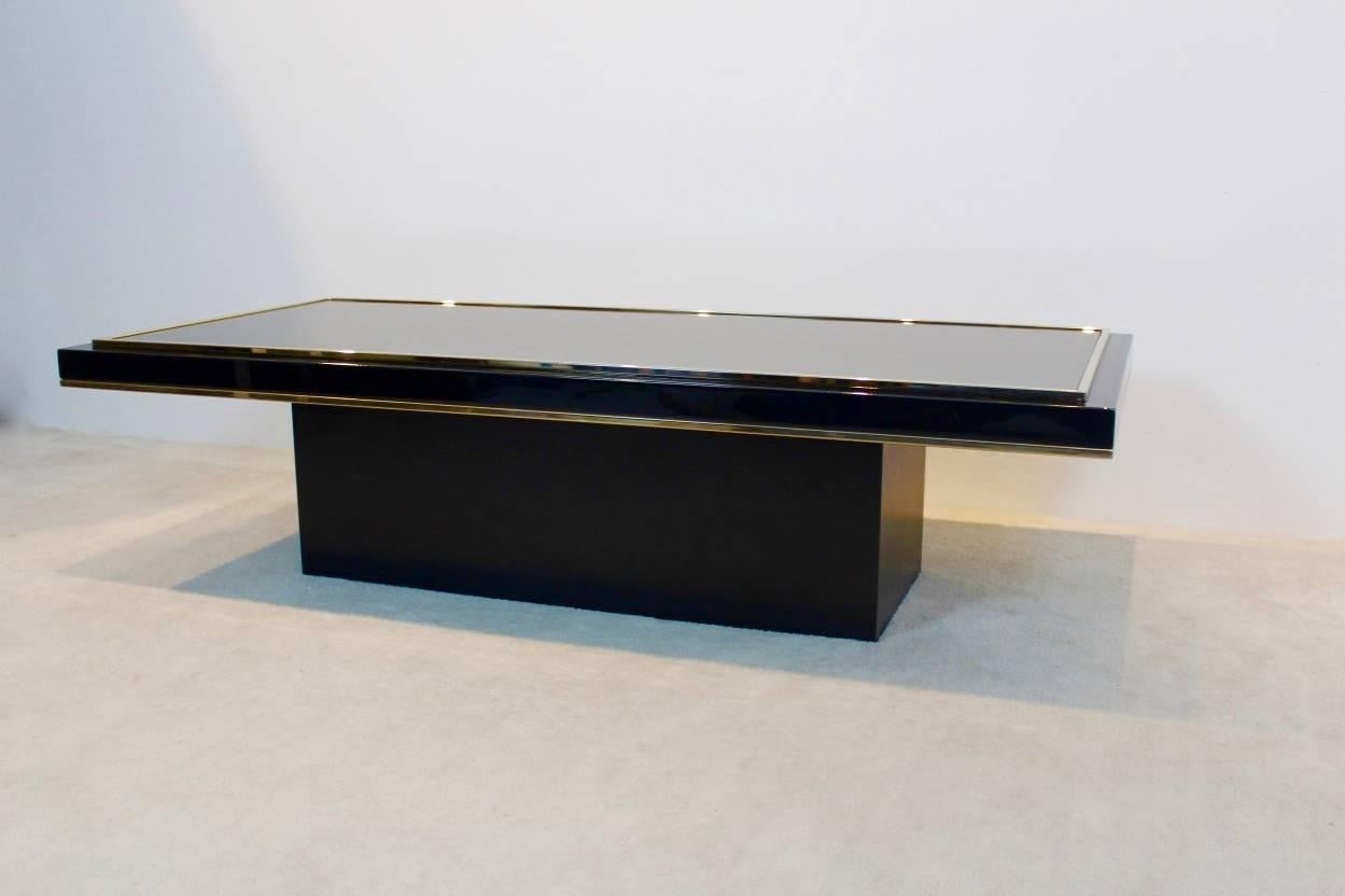 Stunning Belgian coffee table with glamorous performance. The heavy metal frame has a total original black finish with brass and gold-plated surroundings. The table is a unique example of the Hollywood Regency style and in excellent vintage