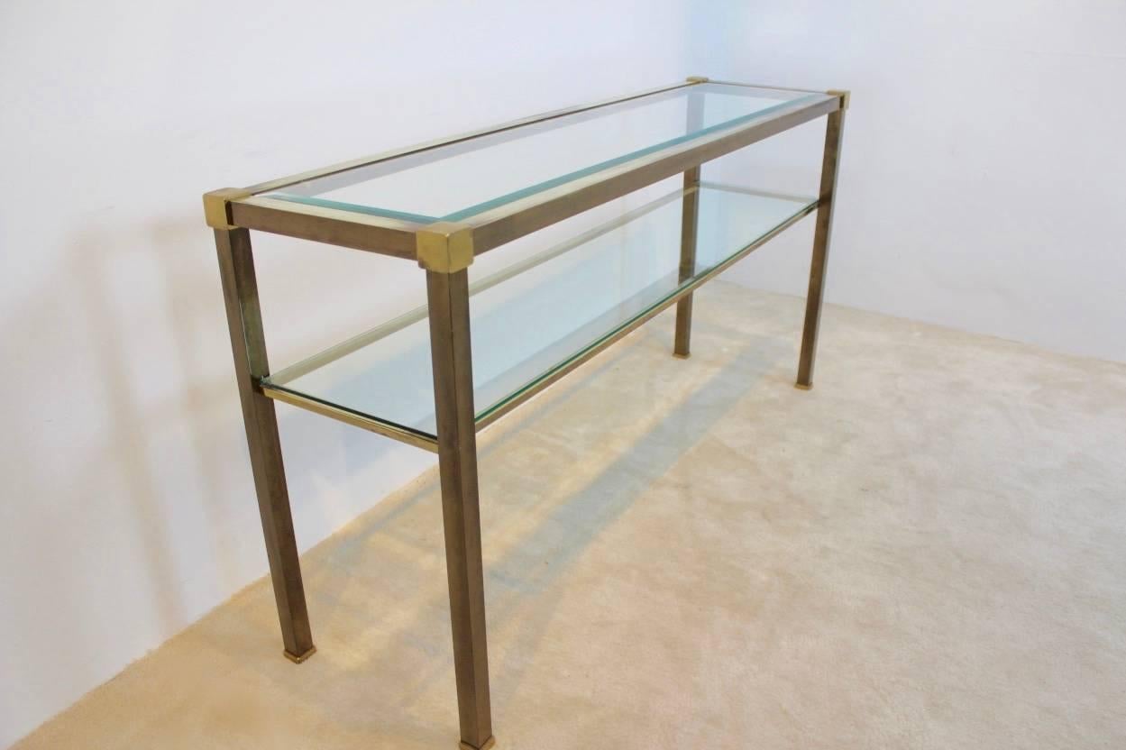 Beautiful two-tiered brass console table made in France, 1970s. Unique patina and strong classy facet-glass top 'Hollywood style. Simple but nice and practical design and high decorative piece and in perfect condition.
      