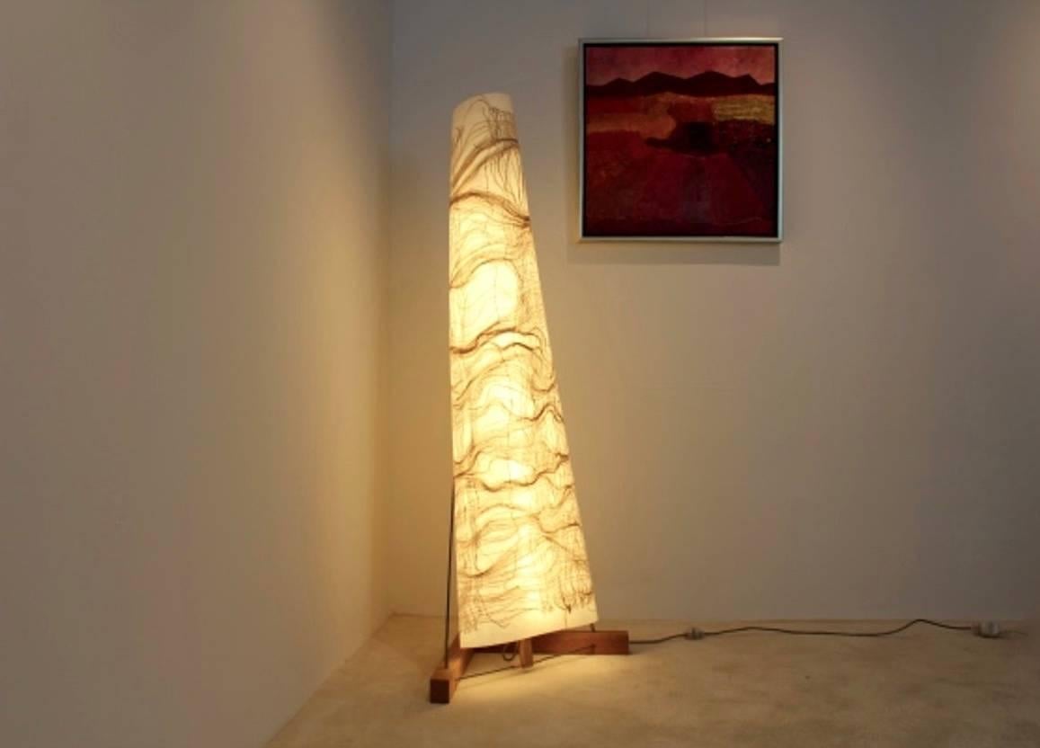 Zeitgenössische Lichtskulptur. Sehr stilvolle Stehleuchte, entworfen und handgefertigt von Lawrence Kwakye. Die Leuchte hat einen massiven Holzsockel, Messingakzente und ein rohes Metallgestell mit einem flexiblen Schirm. Der Lichteffekt ist