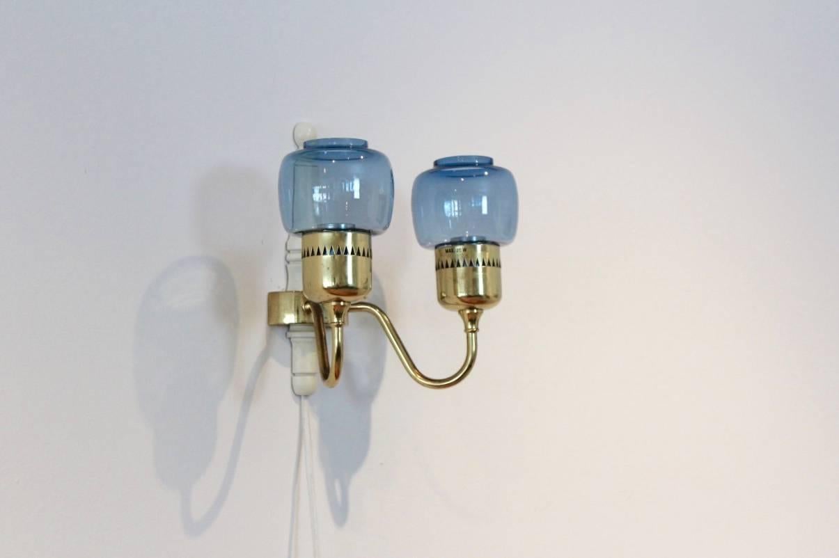 Amazing brass wall sconce model T-526. Designed by Hans Agne Jakobsson AB for Markaryd, Sweden, 1960s. Beautiful Swedish Blue handmade glass combined with characteristic brass. Wall sconce with two arms, each featuring a handmade glass globe. Takes