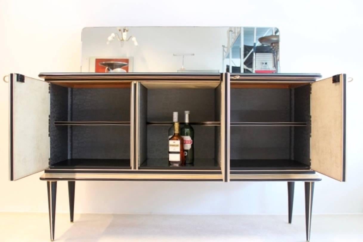 Rare and highly collectible bar credenza designed in Italy by Umberto Mascagni from Bologna. Early 1950s three-door cabinet created with reverse painted glass door fronts, two doors featuring a woman walking down the stairs, the central door
