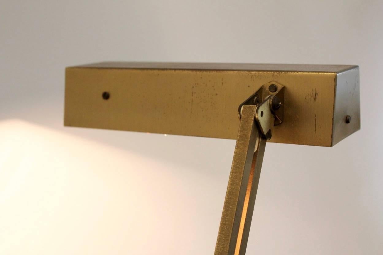 Beautiful German desk lamp produced by Pfäffle-Leuchten Schwenningen, 1950s. The lamp is adjustable and made of brass and shows a lovely patina. Lamp is labeled. Very nice sculptural lines through the double adjustable arm on a wooden base.