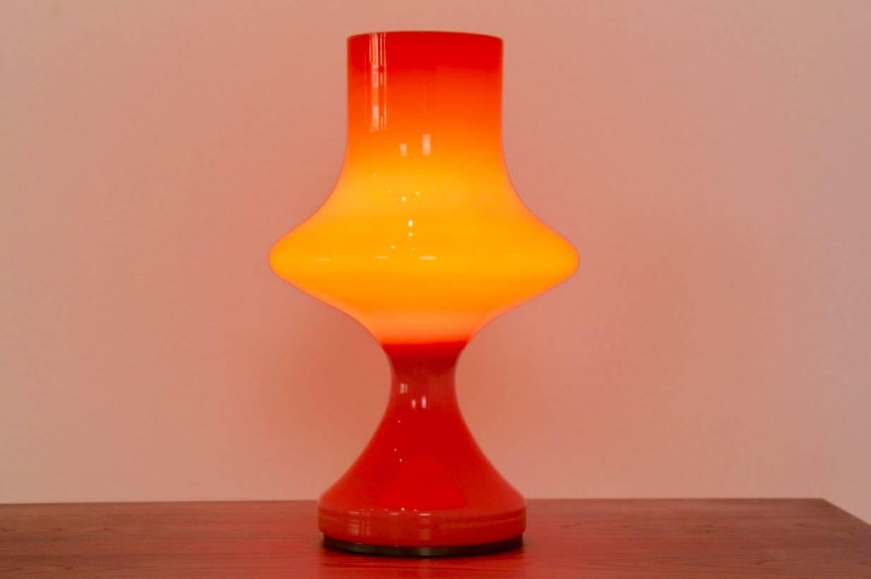 Rare orange glass table lamp. Attributed to Vistosi glassworks in the 1960s. Very beautiful glass. The lamp is blown in one (master) piece, with a small brass-plated metal frame at the bottom. In excellent condition. With beautiful light