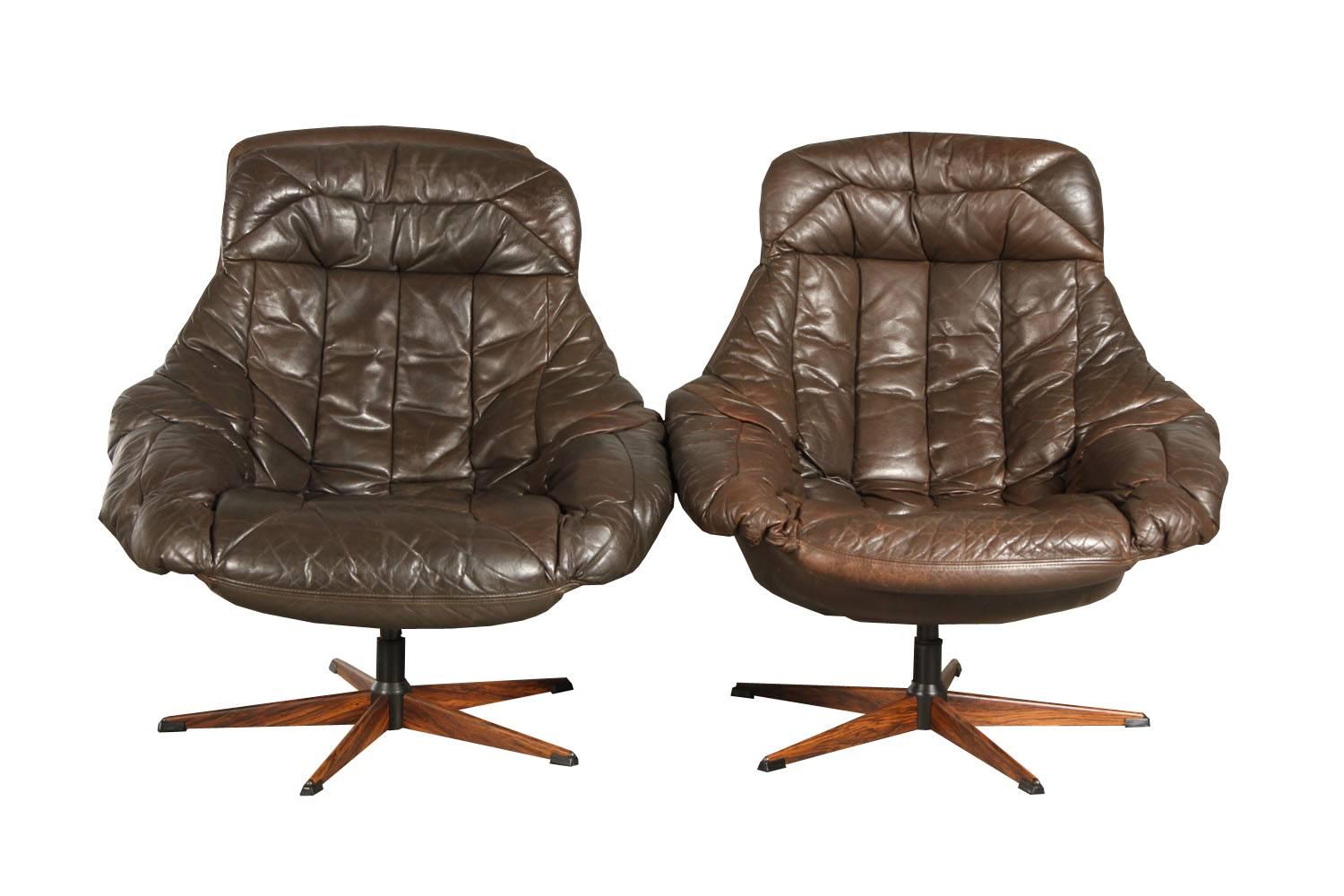 Model silhouette swivels armchairs designed by Henry Walter Klein and produced by Brahmin, designed in the 1970s. 

The armchairs are upholstered in original brown leather and mounted on five-star swivel metal base with faux rosewood