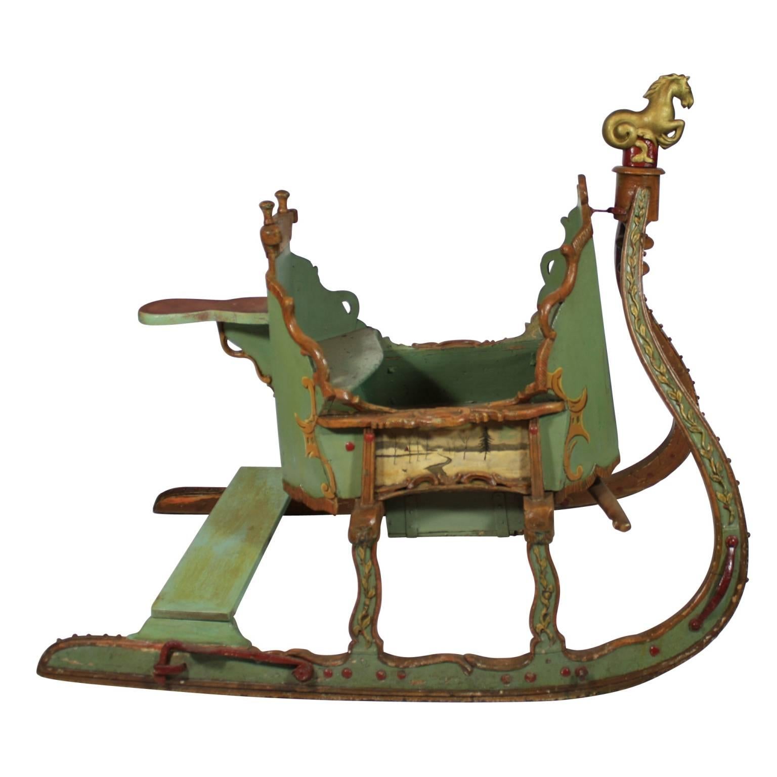 Repainted at the turn of the 20th century, this Russian sleigh still maintains its original style and charm. We love the traditionally bleak Folk Art winter scenes on each side of the sleigh, showcasing the harshness of Russian winters. With a