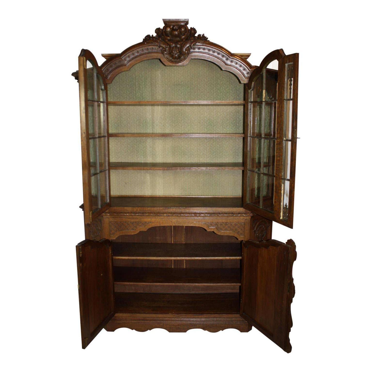This substantial, quarter sawn oak, hutch has seven shelves with upper glass display comprised of windowed glass panels, floral, leaves and shell carvings in the reliefs with simple skirt detailing. The fabric covering in the upper display case can