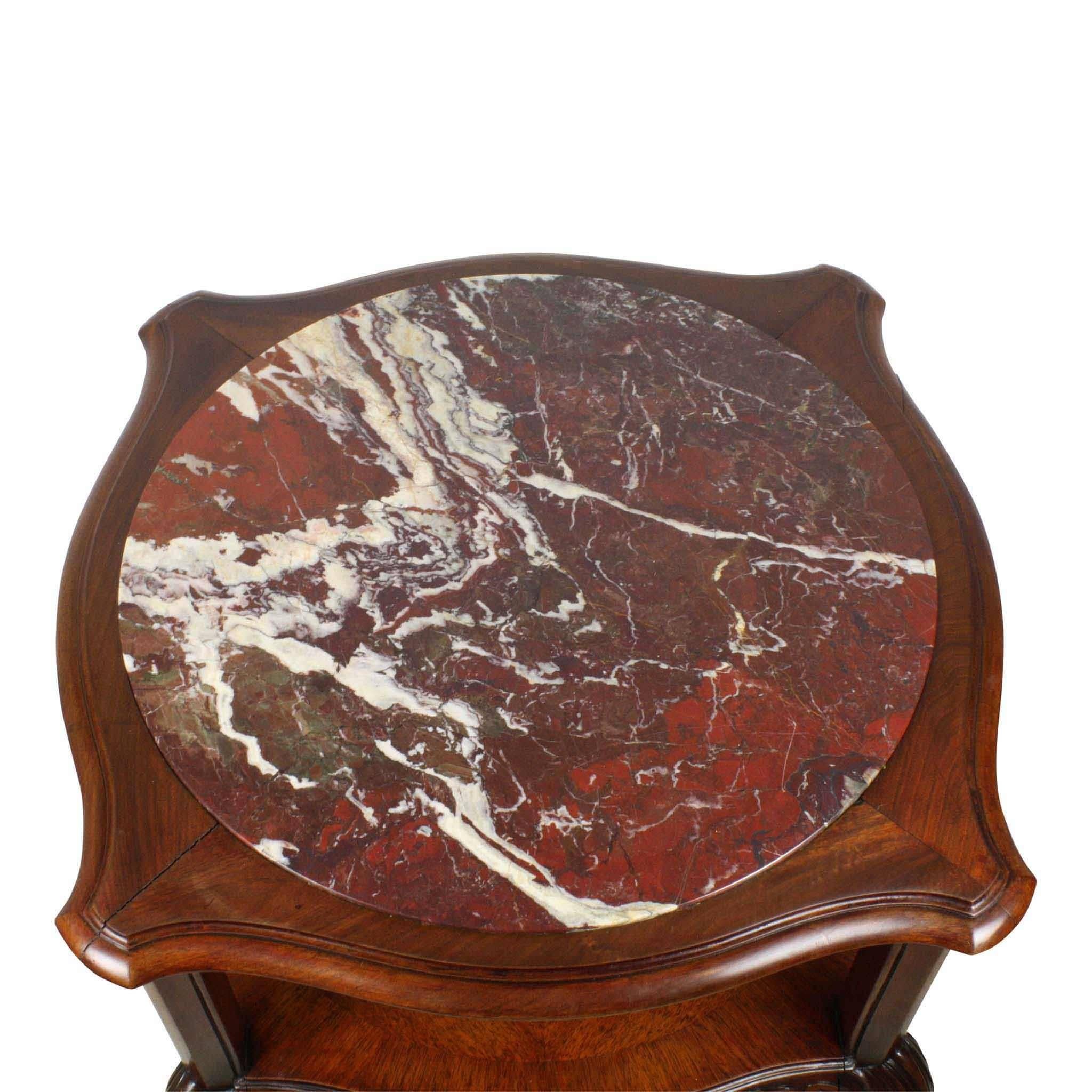 The rich red brown shade of the Griotte marble-top enhances the beauty of this walnut occasional table. The table is semicircular/semi square with simply carved decorative aprons around the top and lower shelf. In the typical style of Chippendale