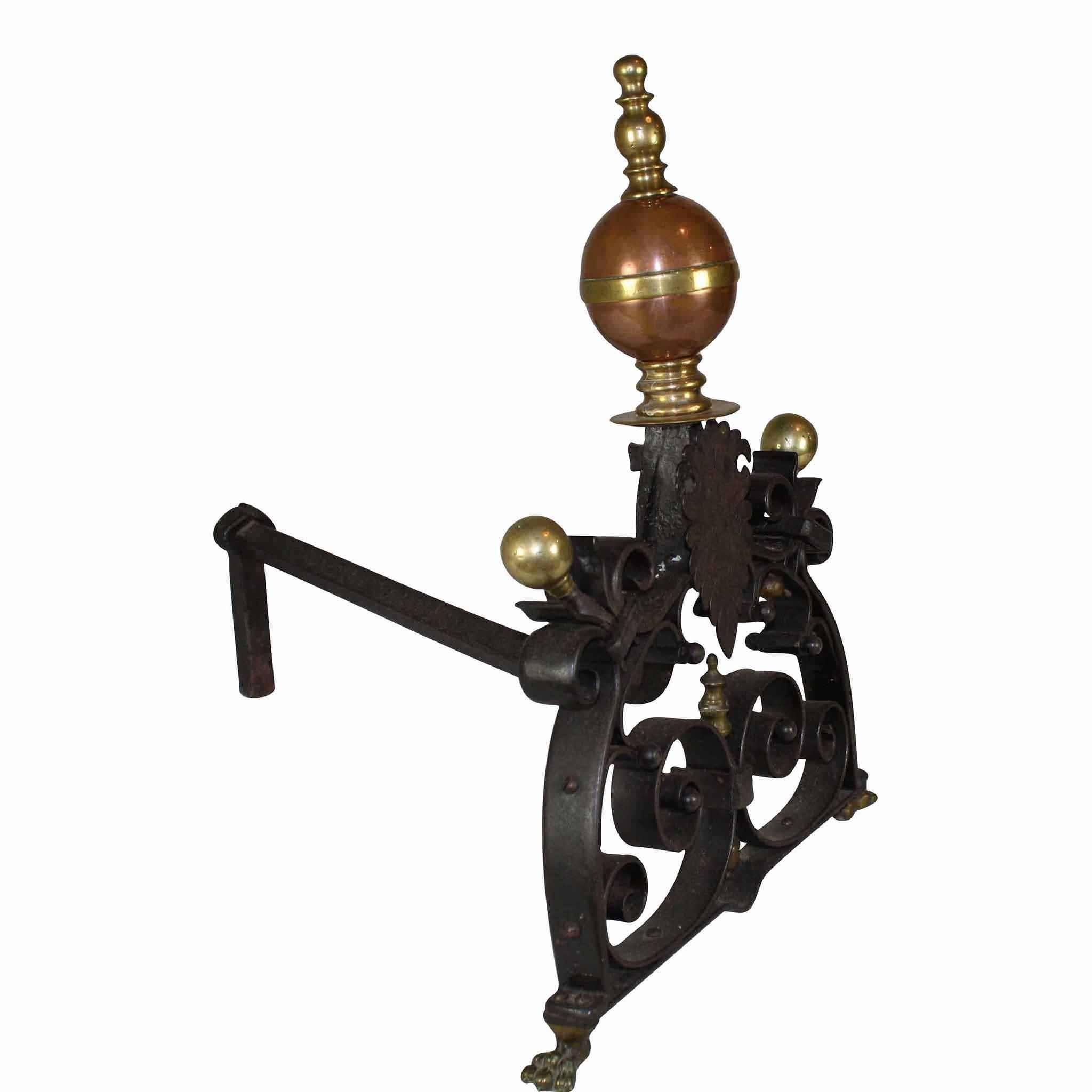 Lovely scrolled iron work gives rise to brass globe finials, the larger center finial features contrasting copper with brass accents, all supported by brass claw feet. These are fully functional andirons and have shanks of 20 inches long.