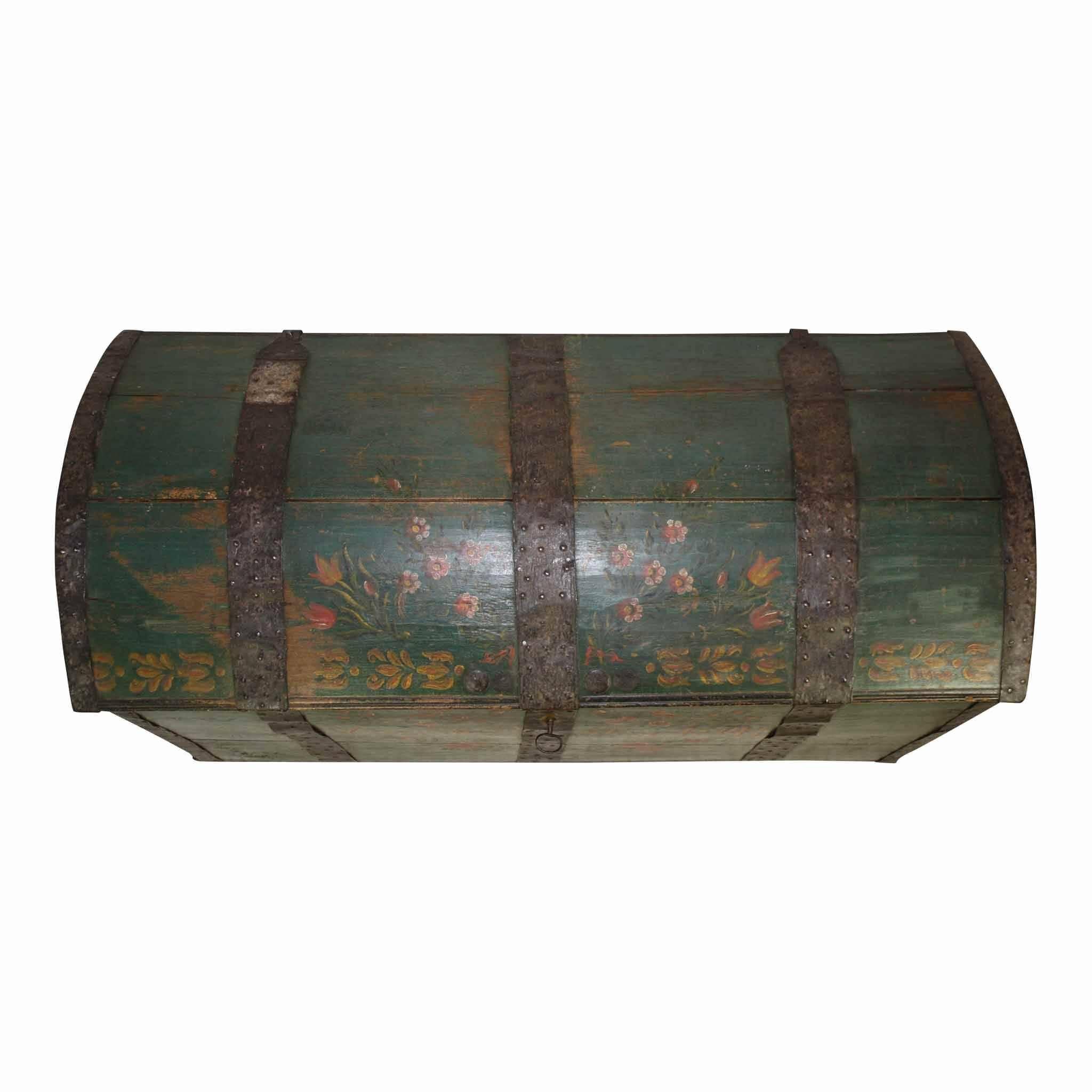 Metal bands and corners lend protection and style to this dome top trunk. A name and a date of 1841 has been painted on the front. A green background with pink flowers and birds decorates the front and lid of the trunk.