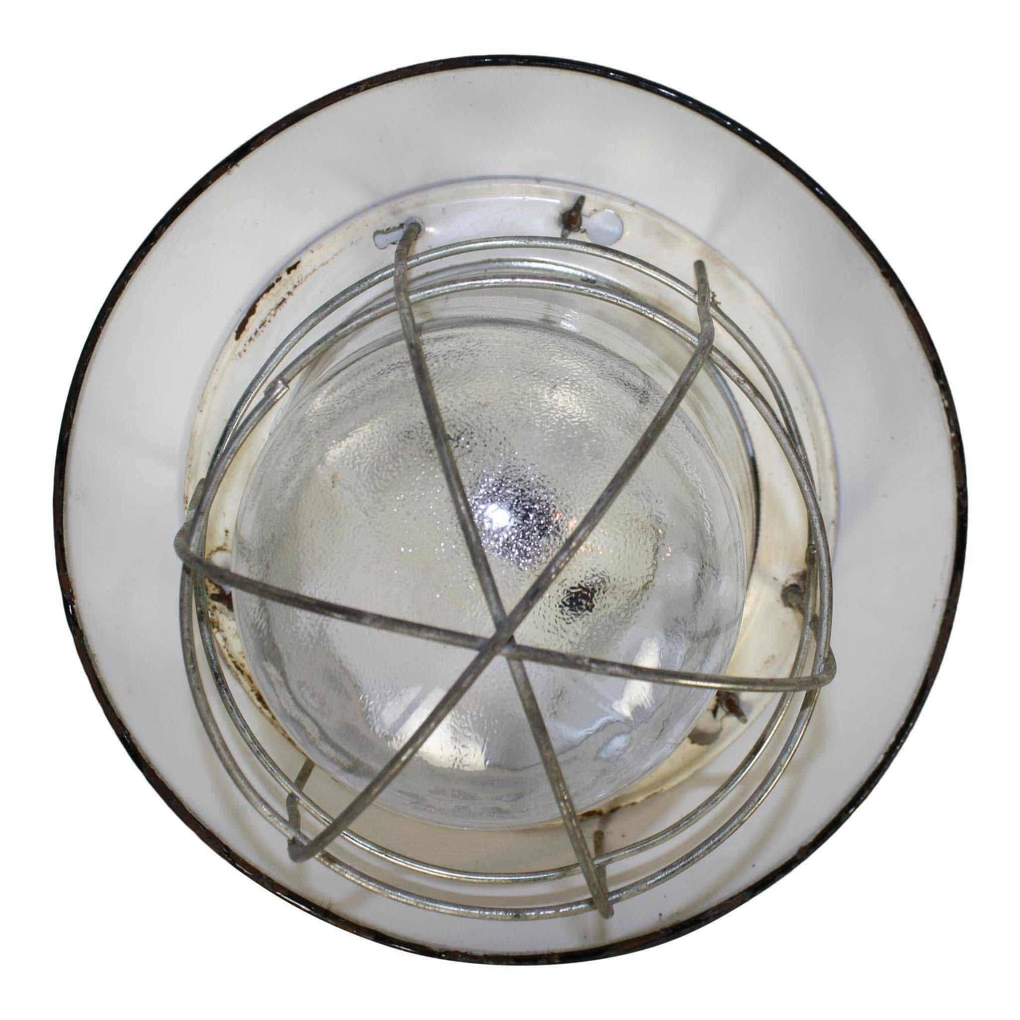 This industrial ceiling light has a black shade and glass globe with a cage. It is not wired but can be easily wired for use. 