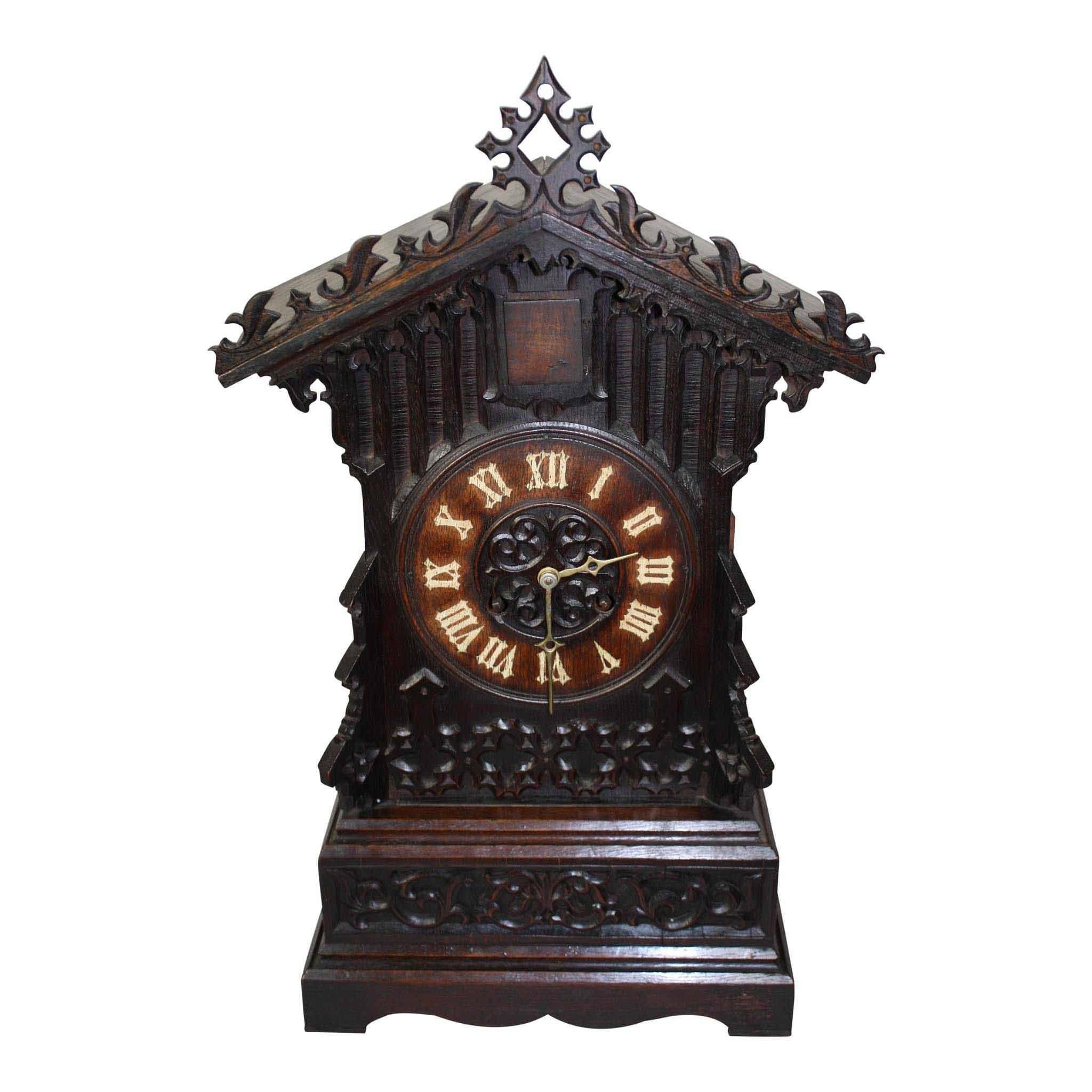 A beautifully carved, wall-mounted shelf, holds this German Cuckoo clock. Carved vines, leaves and star patterns are applied to a simple and elegant case. Delicate brass hands with painted numerals on a 7.5 inch clock face. Working order. Key