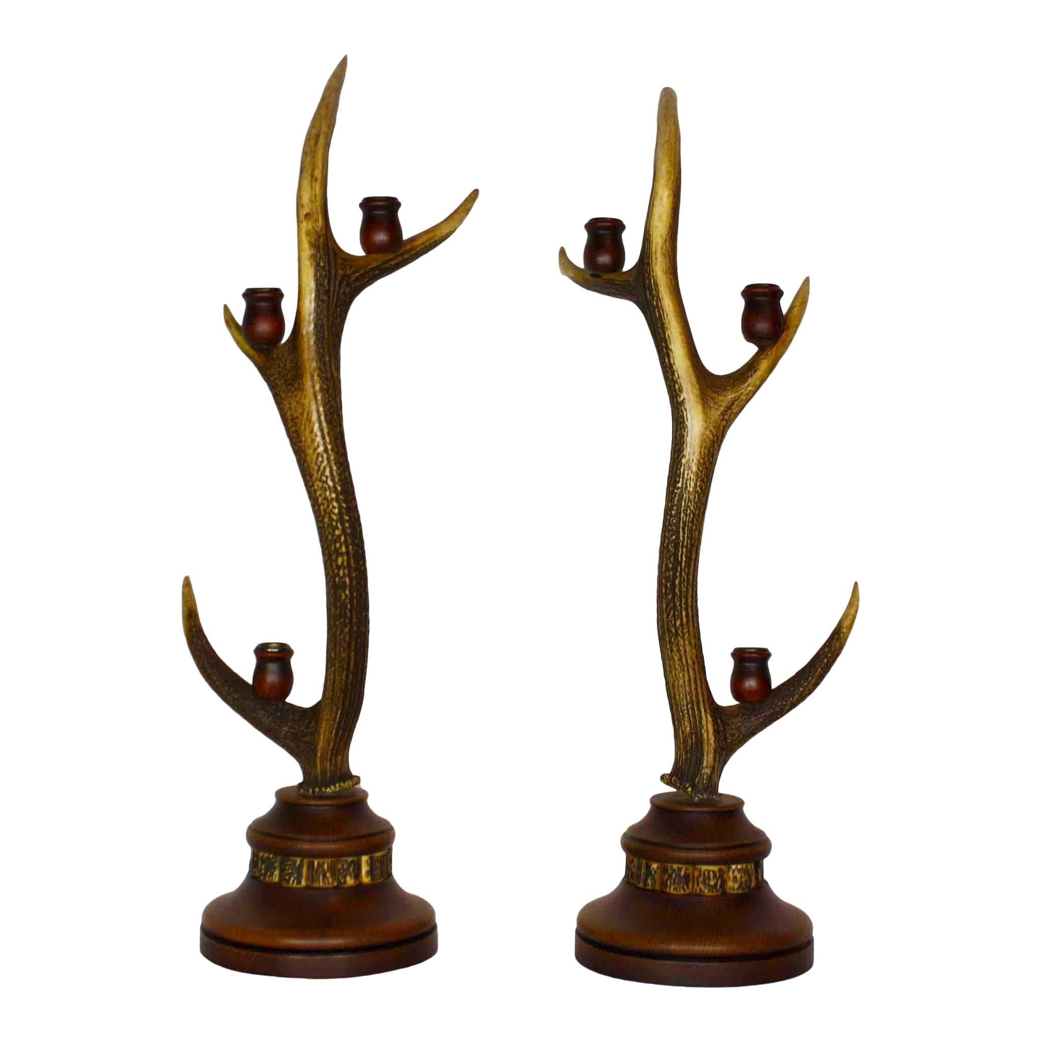 Crafted from antique European red stag antlers, this eight point candelabra set has three, wood and brass candle holders on each antler. The wood bases are accented with a ring of decorative antler pieces. One of the antlers has a broken tine.