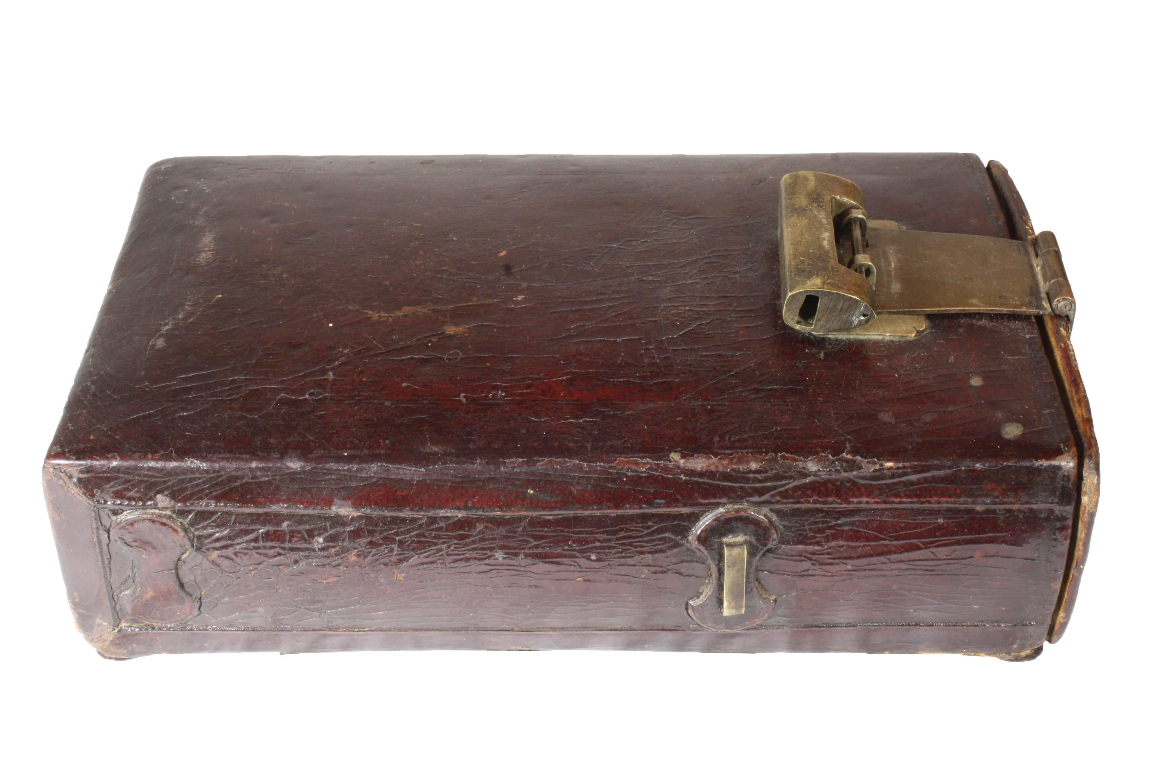A brown mahogany leather case of a type that was used throughout Asian countries for storing opium and opium smoking accessories. With the original brass lock and key featuring a typical engraving of a blossoming cherry tree. A similar item can be