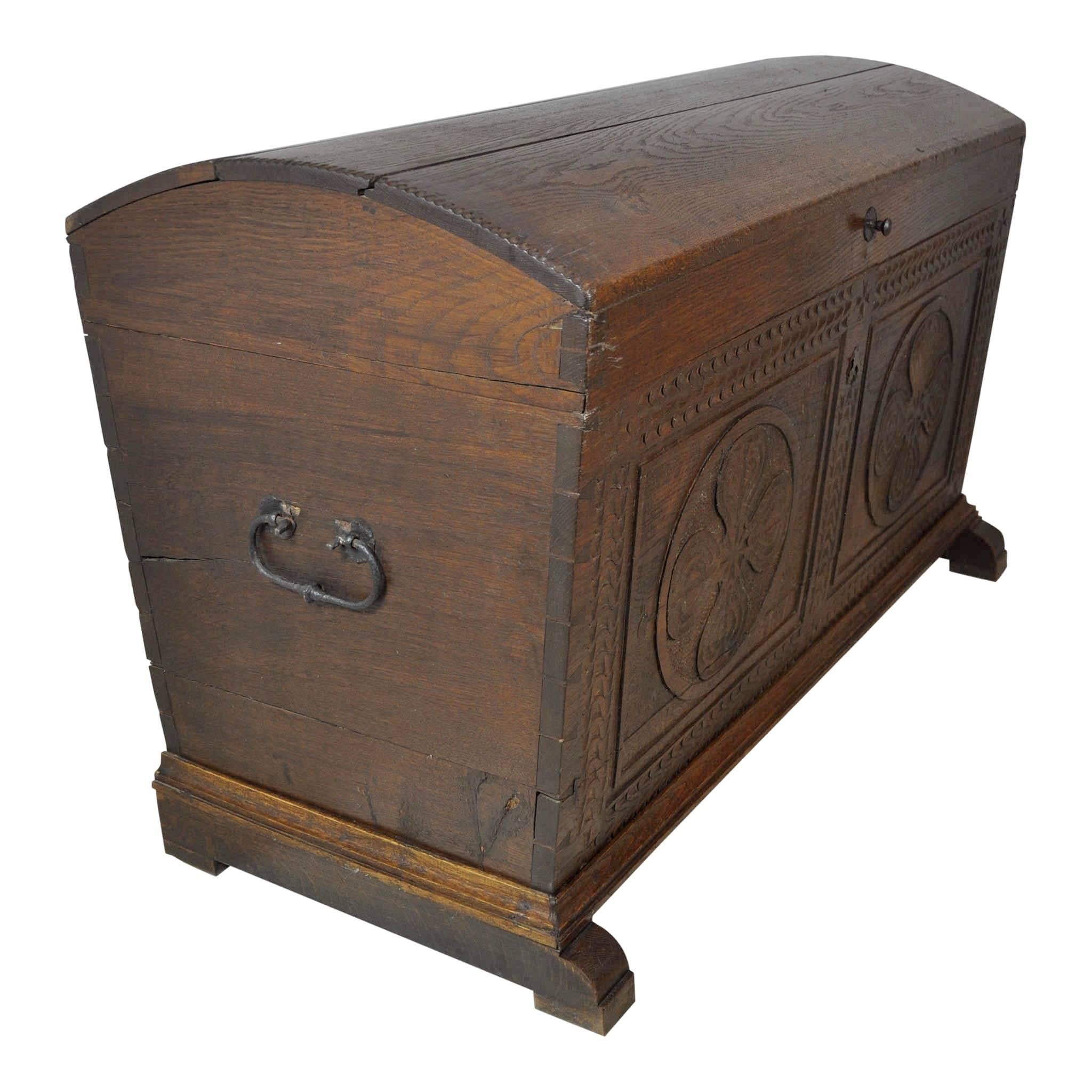 The front of this domed oak trunk features two panels with relief carvings of circles enclosing quatrefoils. The trunk's corners feature exposed dove tailed joinery and the domed top with its double rabbet joints and wooden pins adds to the charm of