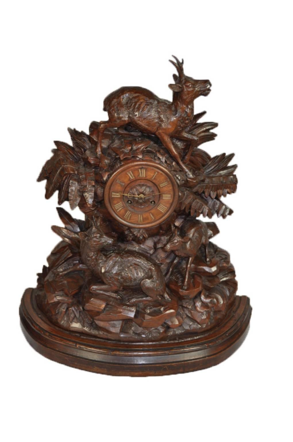 A nicely carved walnut clock featuring a family of three roe deer flanking a carved clock face with inlaid brass numerals. Two matching candelabras, each with one roe deer, hold three tapers each. The fully functioning, serviced clock comes with key