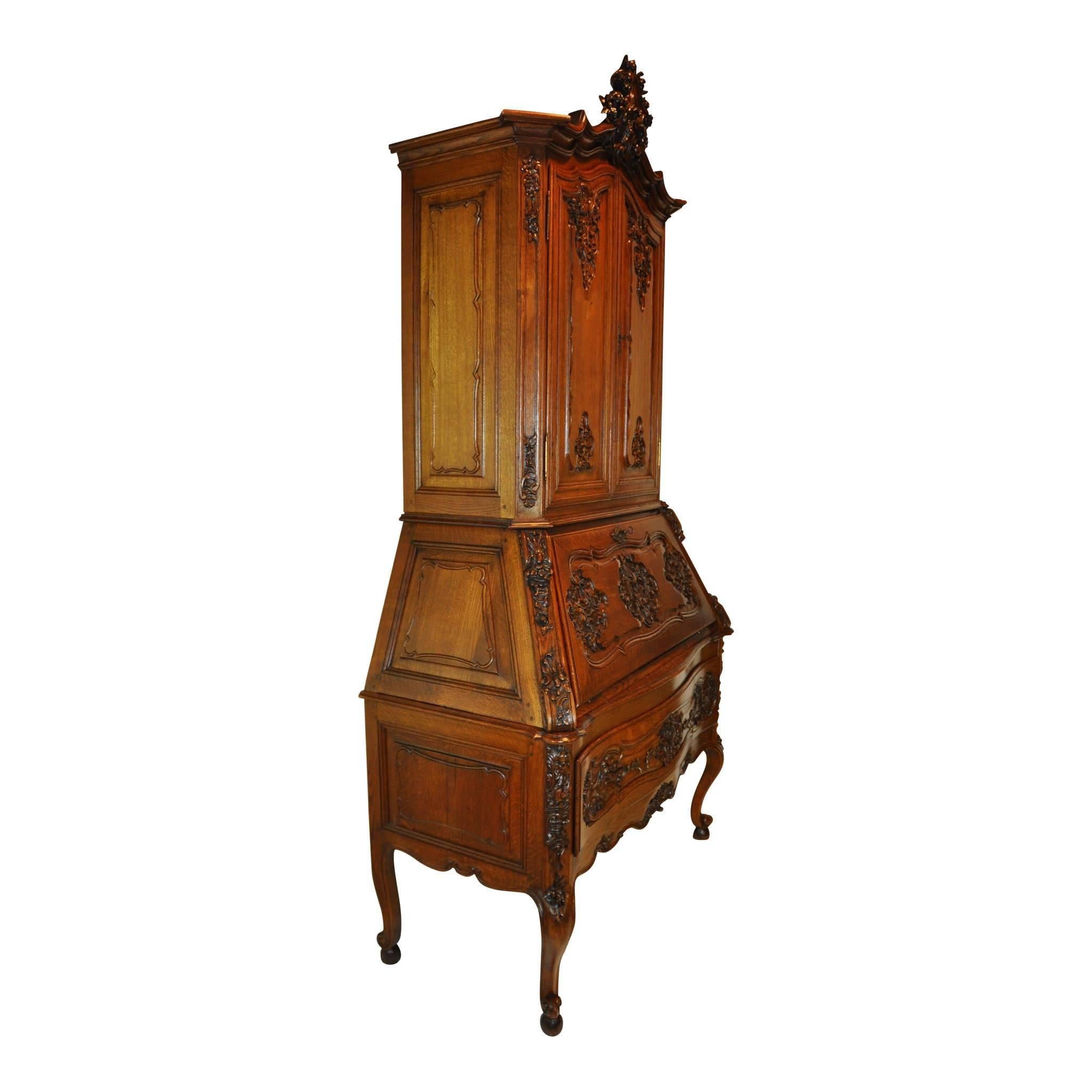 This beautiful quarter sawn oak secretary is comprised of three pieces. It features a top shelf cabinet with two shelves, a middle section with a drop down writing surface and eight compartments, and a base with a wide, deep drawer on cabriole legs