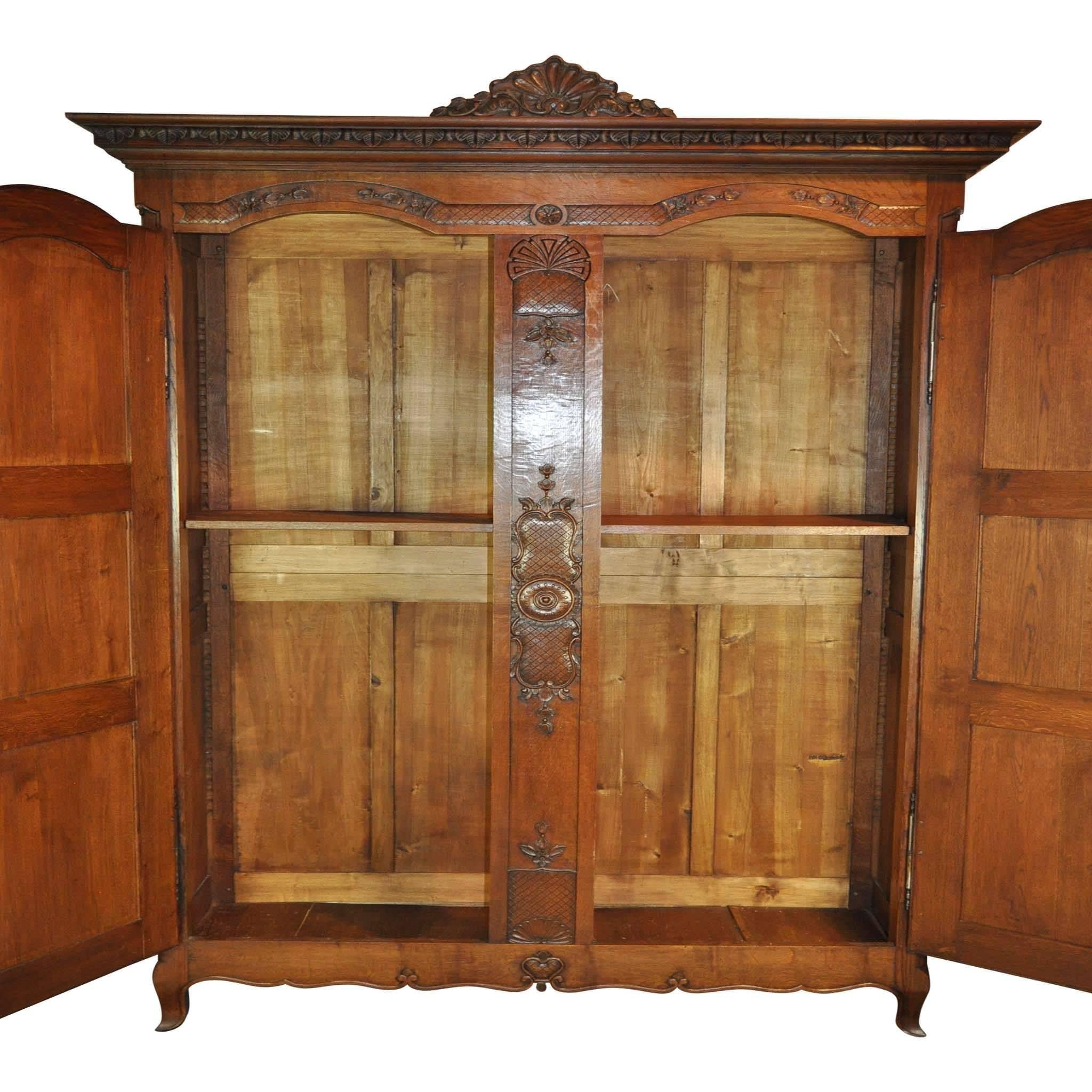 Acanthus leaves, shells and flowers decorate the panels and crown of this large armoire. A center panel separates the two doors, which each have a key. The interior has one adjustable shelf. Made from beautifully flecked quarter sawn white oak.