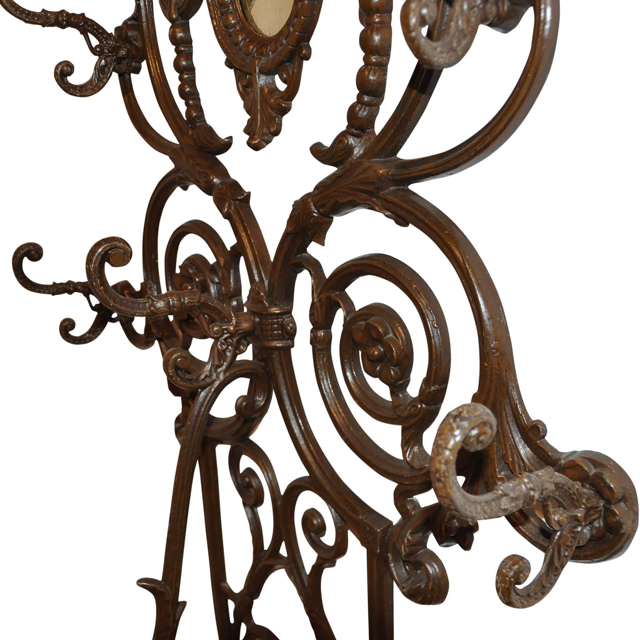 The elegant design includes flowers, acanthus leaves, and scrolling. It has eight double hooks, an oval mirror, and a removable drip pan in the umbrella stand.