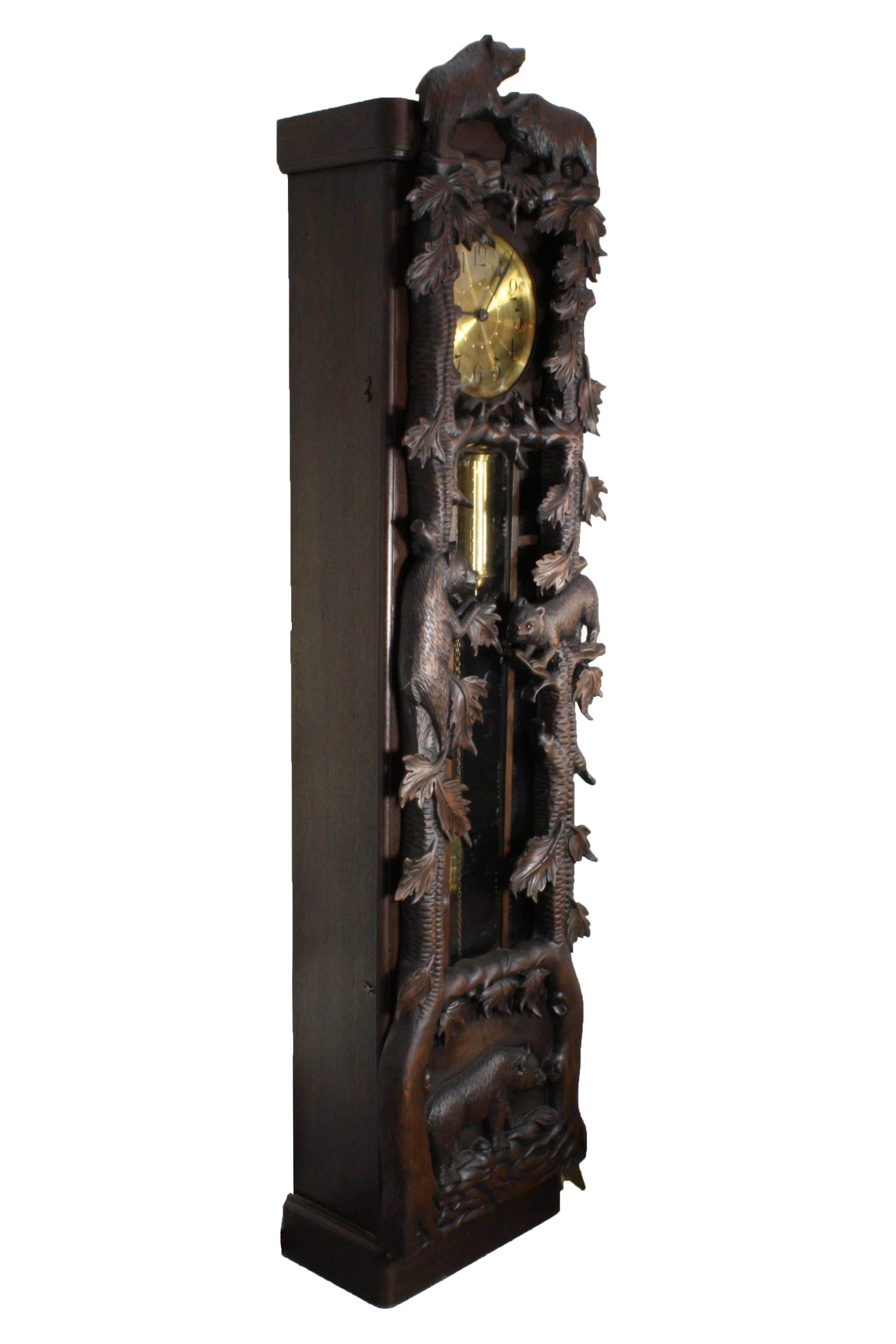 A large and dynamic carved front case featuring trees and playful bears with glass eyes. The brass clock face, with Arabic numerals, brass weights and pendulum offer a stunning contrast with the darkly stained oak case. The fully functional and