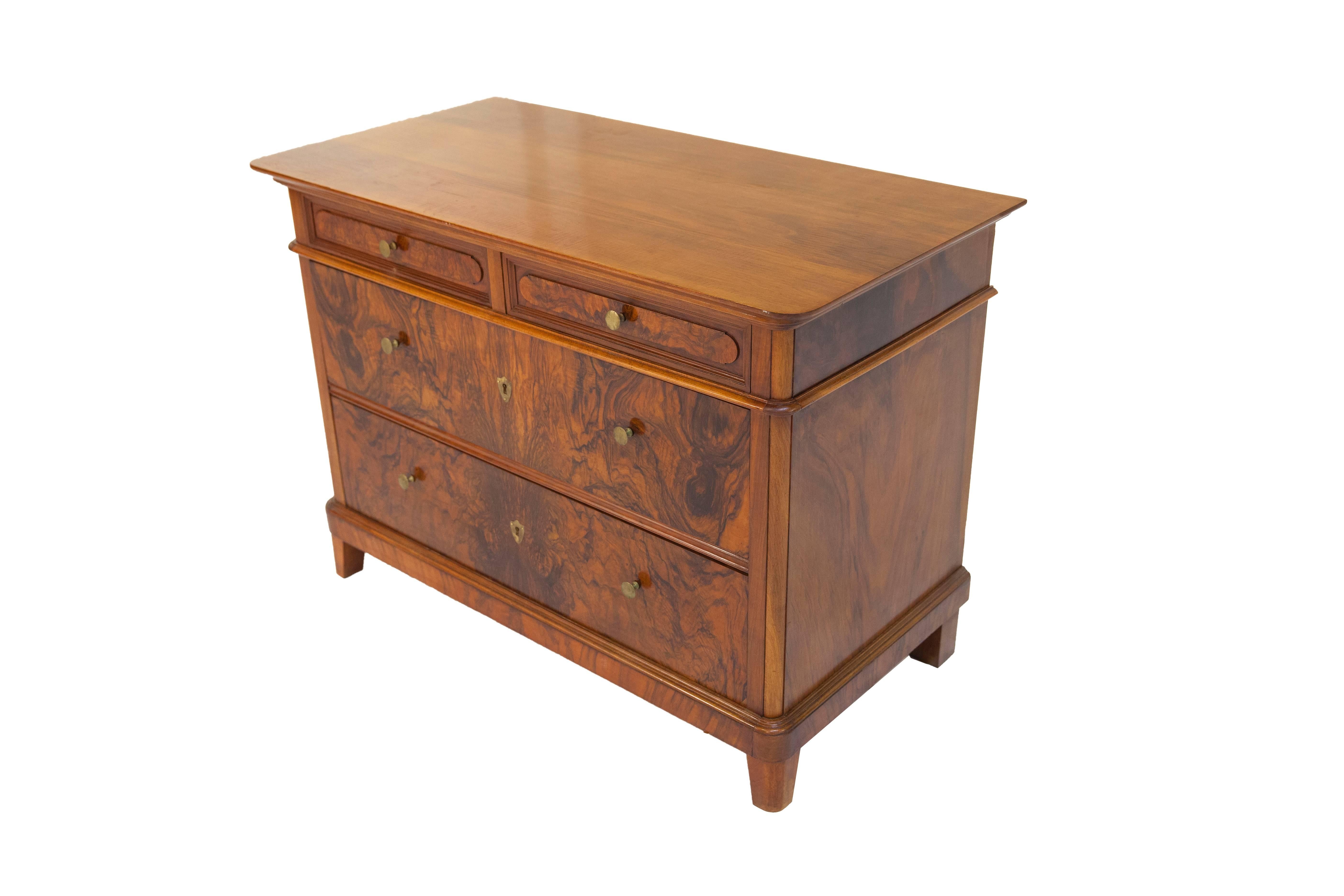Below its cover plate, the chest of drawers features two drawers side by side, and below these, two spacious drawers, one above the other. The front sides of the drawers are fitted with mirror-inverted walnut and root wood veneer. The sides and