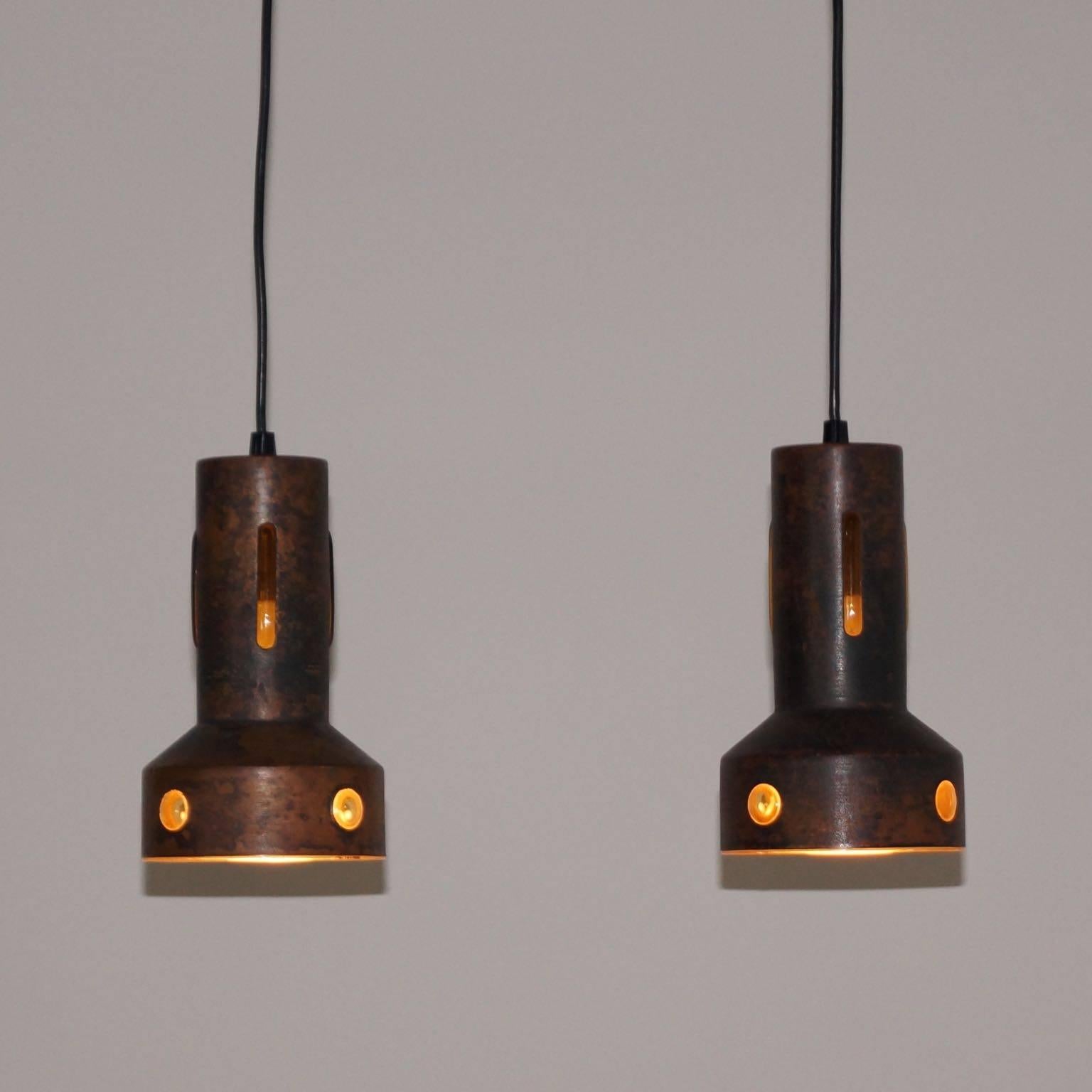 Pair of copper pendant lights of Nanny Still attributed to RAAK, circa 1960. A special feature of these lamps is the perforated cap, made of copper in which a layer of yellow colored glass is blown to the inside. This technique results in a very