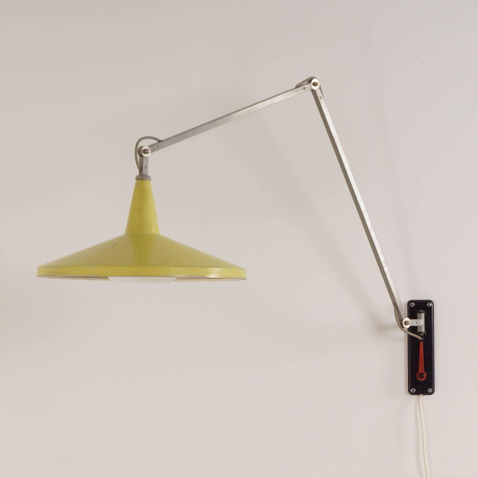 Rare yellow Panama wall lamp model no. 4050 by Wim Rietveld for Gispen in 1956. The lamp has three hinges, so it can be put in different positions (with the red key, attached to the wall plate). The hood is yellow and has the shape of a hat and is