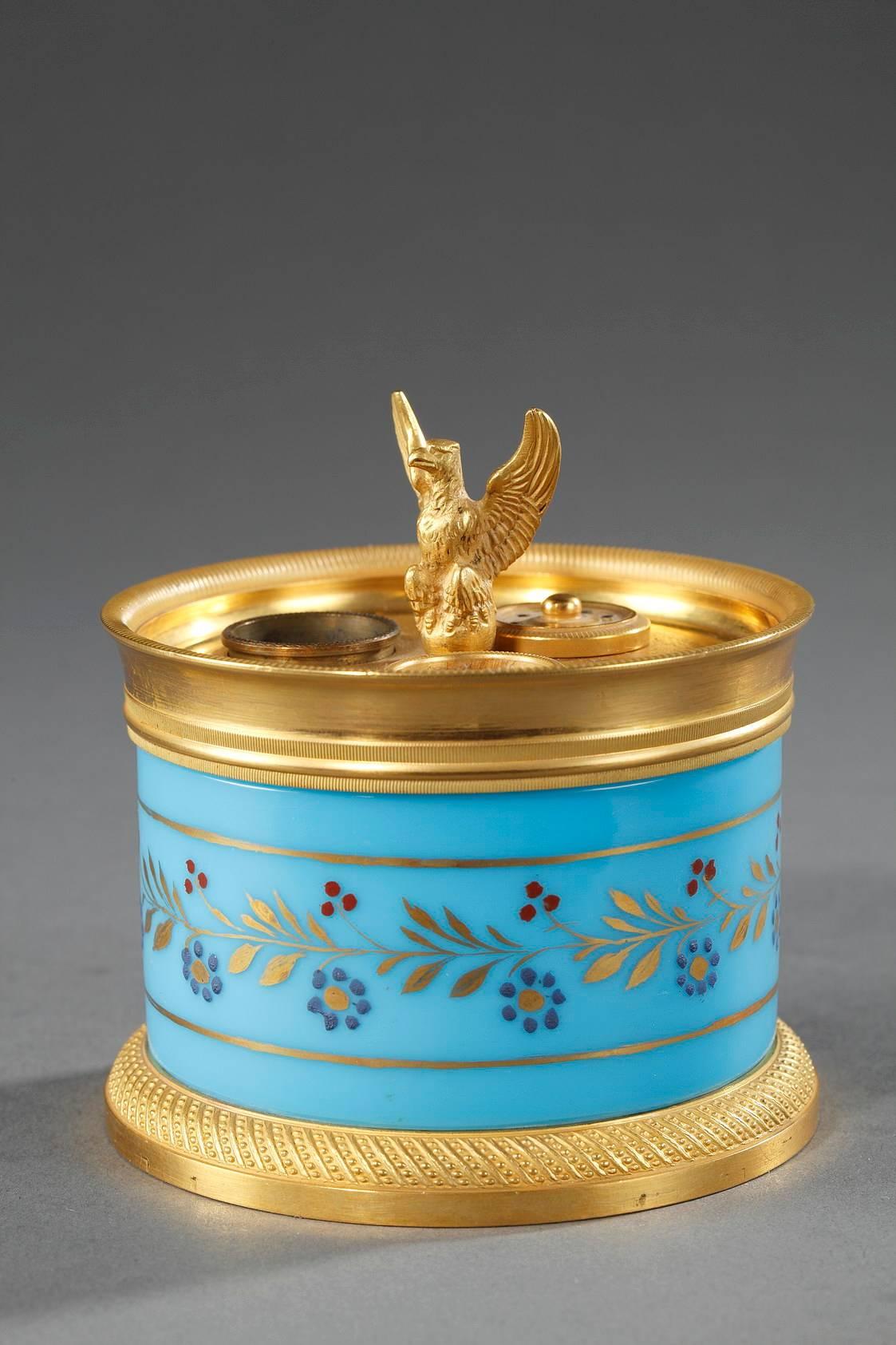 Small, circular inkwell in turquoise opaline with two inkwells and a pounce pot. It is mounted with gilded bronze that is intricately decorated with ribbing and spiraling beadwork. The body of the inkwell is decorated with a ring of gold leaves with