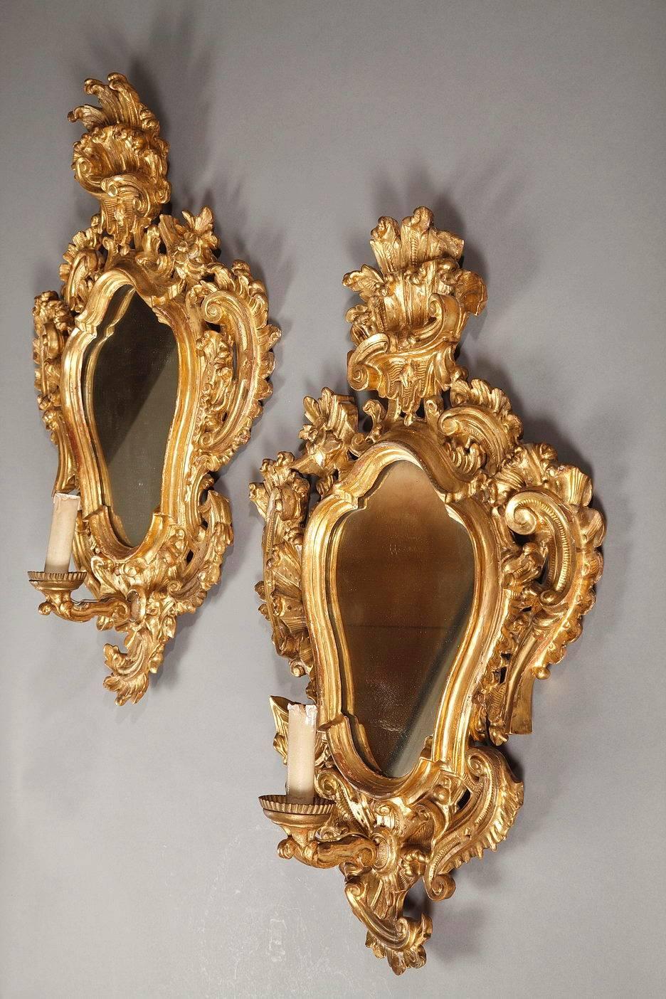 Pair of Italian mirrors in giltwood, richly decorated with openwork scrolling, foliage and flowers. At the bottom of each mirror is a candle arm embellished with fluting,

circa 1750.

Dim: W: 20.9 in – D: 6.7in – H: 29.5in.
Dim: L: 53cm, P: