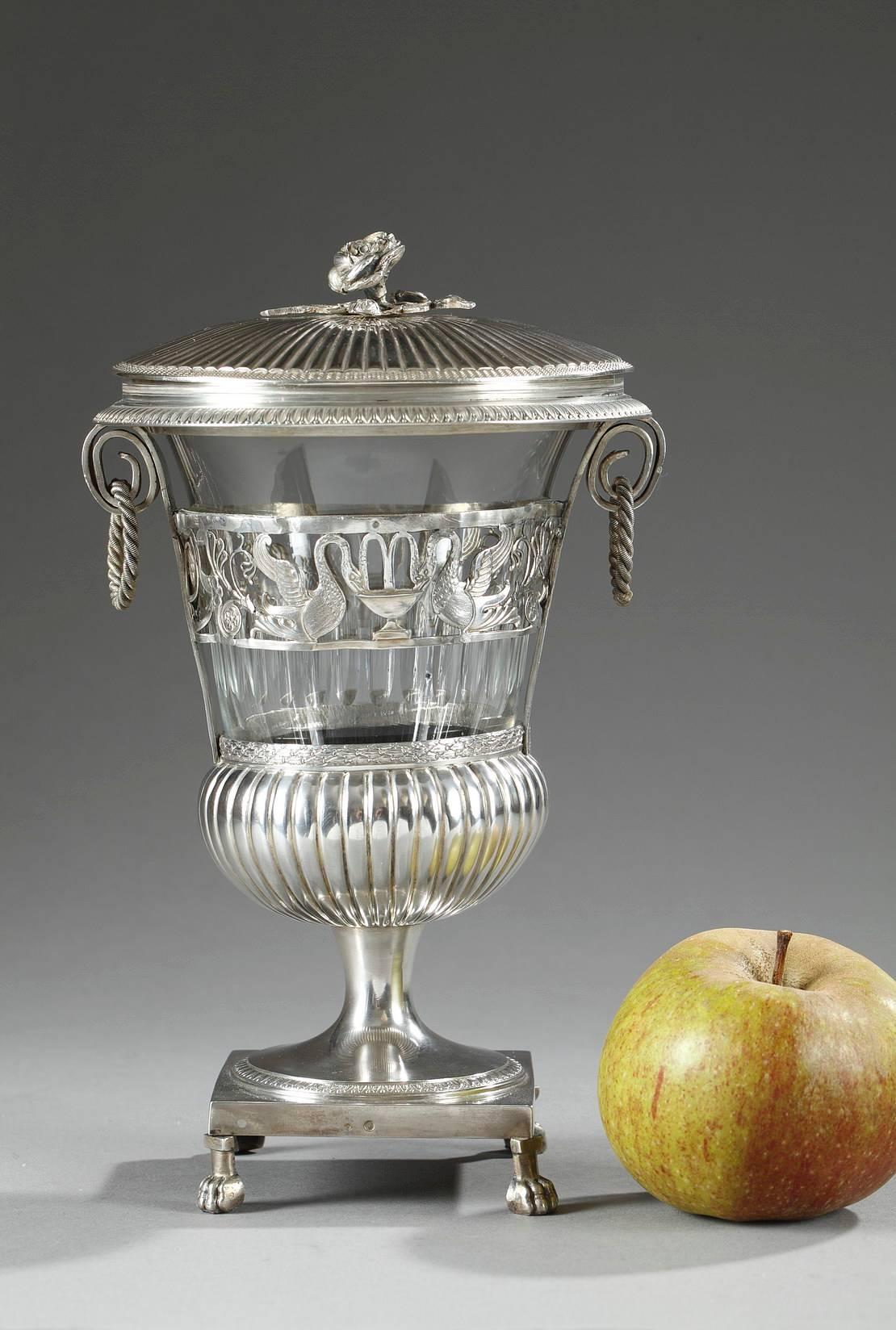 Early 19th century candy dish in silver and crystal. Its silver lid is accented with gadrooning that radiates out from a rose that forms the handle of the lid. The crystal body is set in openwork silver and depicts swans drinking from a fountain,