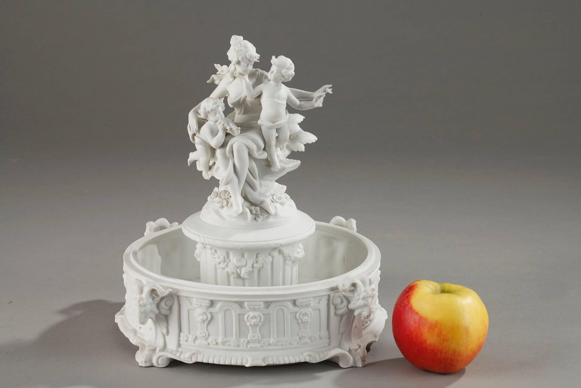 Biscuit porcelain centerpiece with musical cupids sculpted biscuit porcelain group featuring cupids playing music in the company of a young woman wearing a flowing gown, seated on a rock. The ensemble rests on a naturalist flowerbed set on a