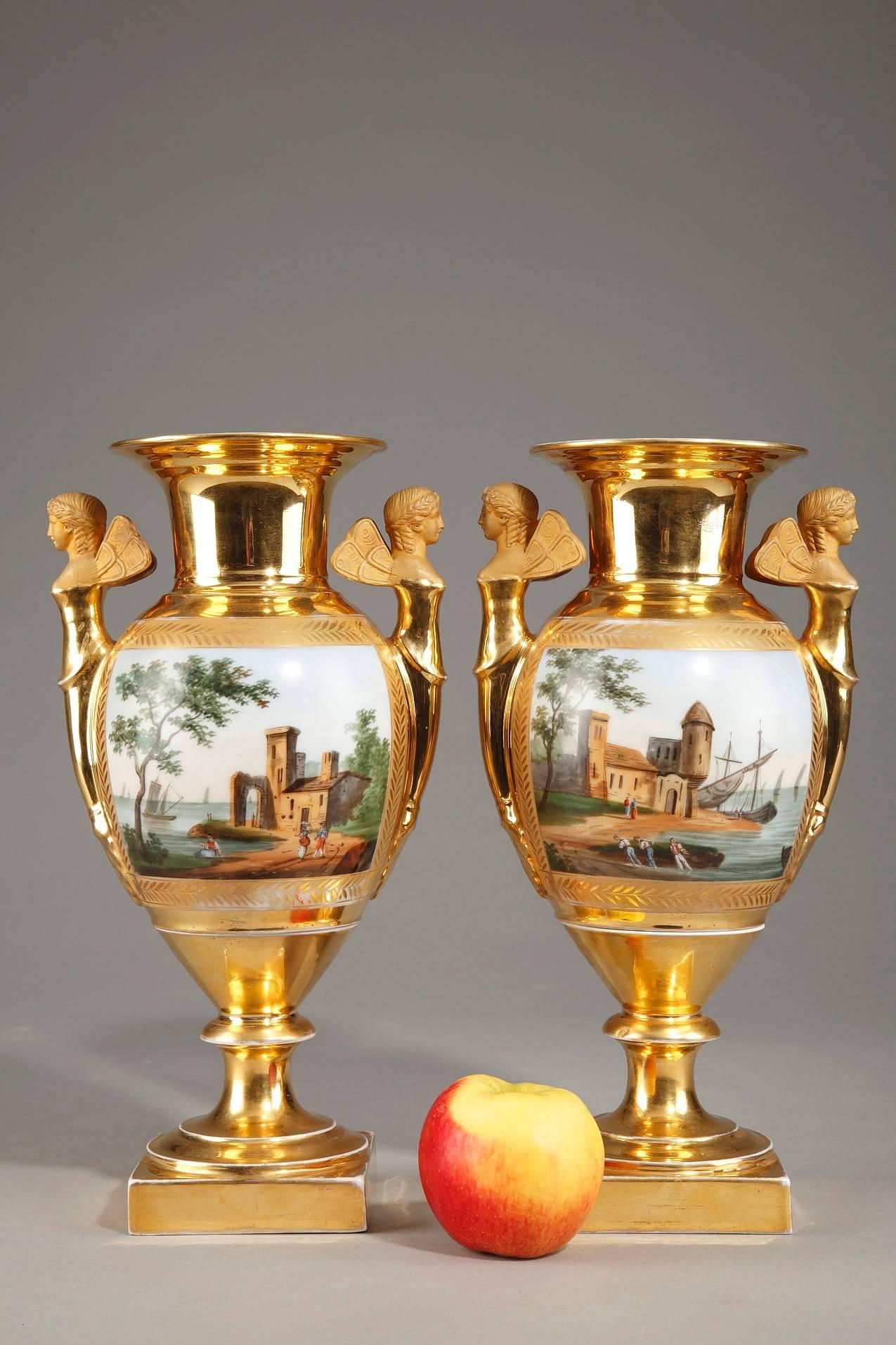 Pair of oval-shaped, porcelain vases with tiered stems on rectangular bases. The short handles of the vases are in the shape of winged women. The bodies of the vases are decorated with domestic scenes on one side and seaside landscapes on the other.