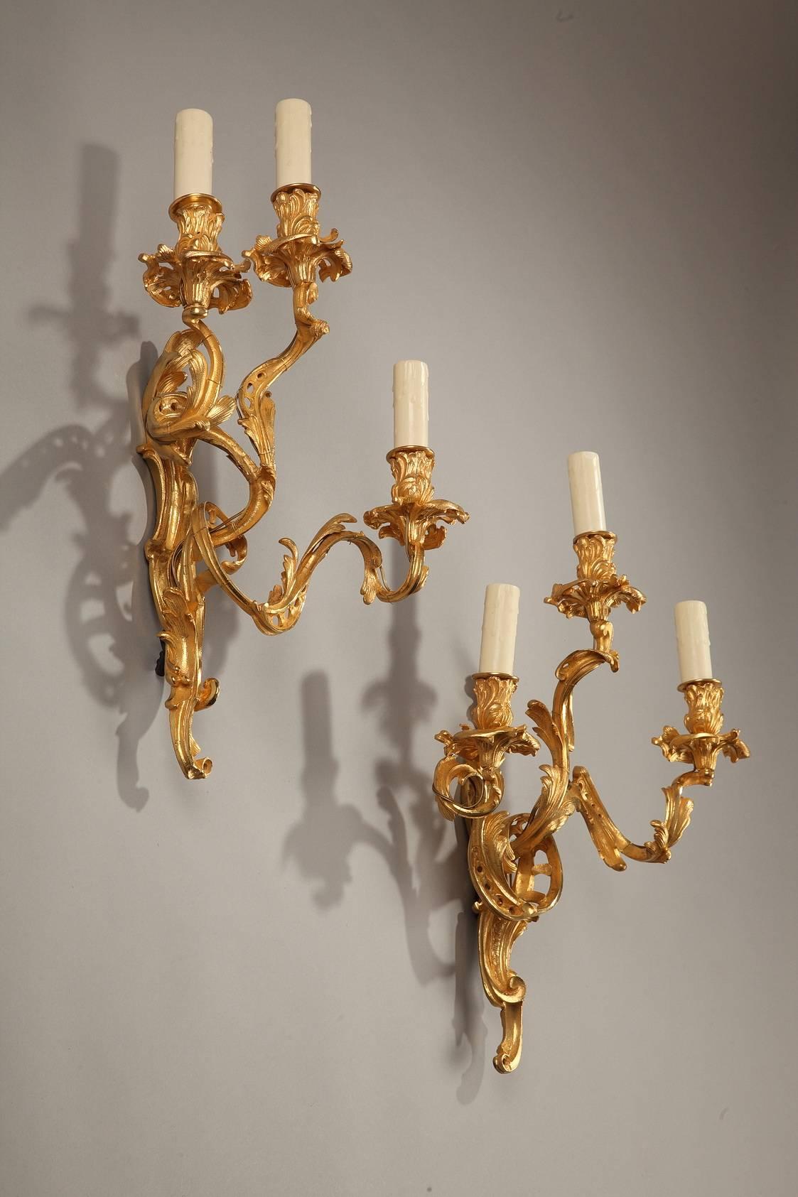 Sizable pair of Louis XV-style bronze sconces. Each sconce features three branches of lights that are sculpted with acanthus leaves, openwork coiling and gadrooned foliage. Electrified.
 
circa 1880.

Dimensions: L: 12.2 in, W: 5.1 in, H: 19.7