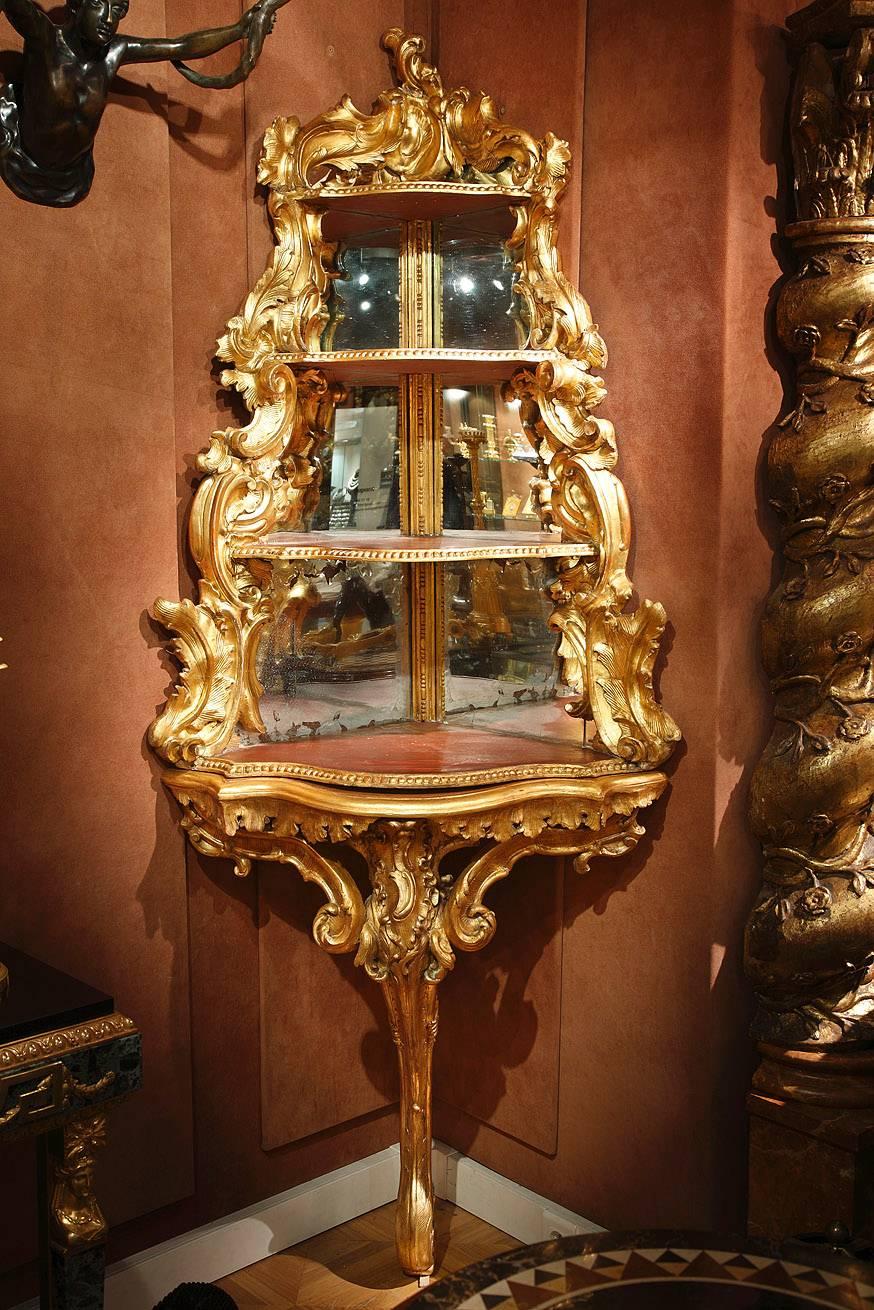 Substantial gilded wood corner console embellished with intertwining curls and leaves. The upper portion is composed of four receding triangular shelves whose exterior edge is in the same shape as the base of the console. The edge of each shelf is