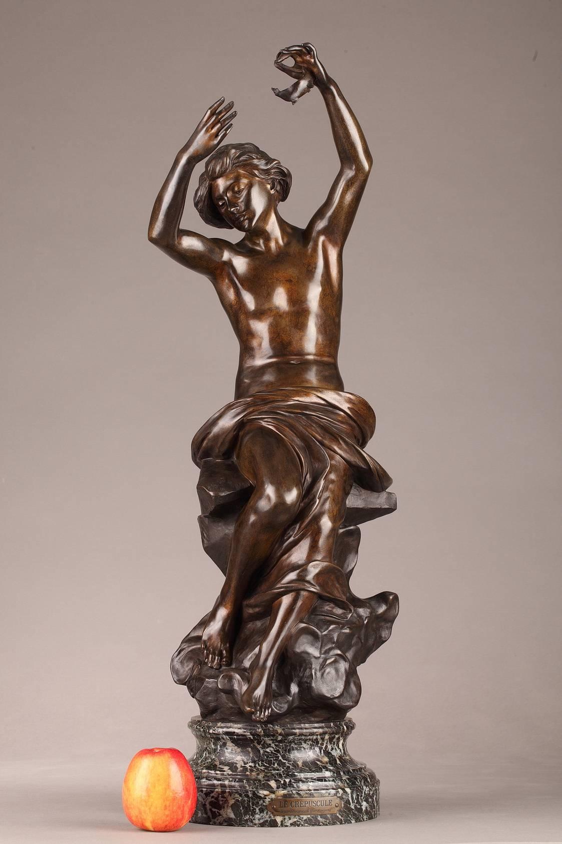 Bronze sculpture in brown patina featuring a young man seated on clouds. His arms are lifted and he is holding an oil lamp, symbolizing the coming night. The sculpture is set on a circular, green Maurin marble base.

Signed: MADRASSI