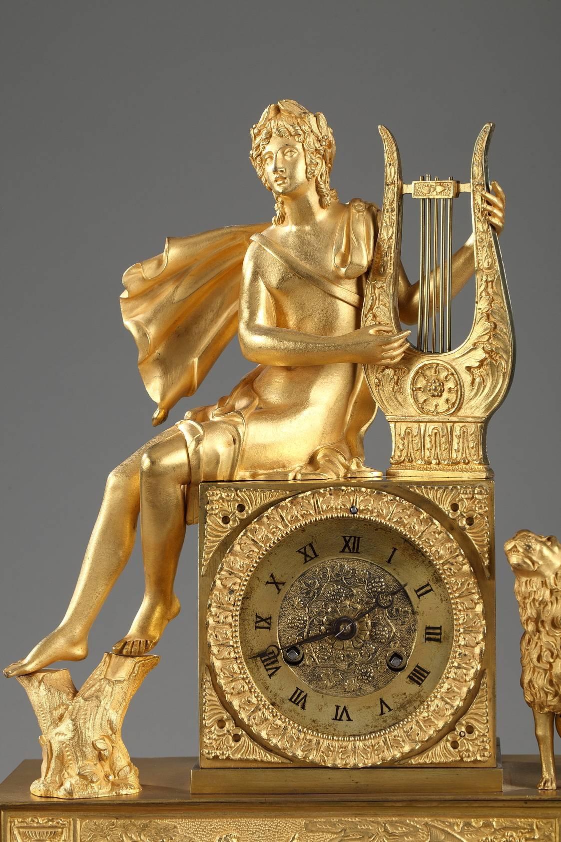 Early 19th century gilt and chiseled bronze mantel clock. It features Orpheus playing his lyre near a lion. He is seated on the clock casing where the Roman numerals mark the hours. The ensemble rests on a rectangular base decorated with a frieze