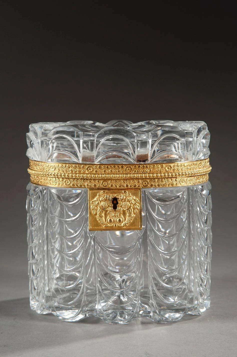 Beautiful oval jewelry box in cut crystal decorated with stylized waves. Radiating lines are etched in the crystal glass lid. An intricate cornucopia and flower design embellishes the sculpted and gilded bronze frame,

circa 1820.
Dimension: L: